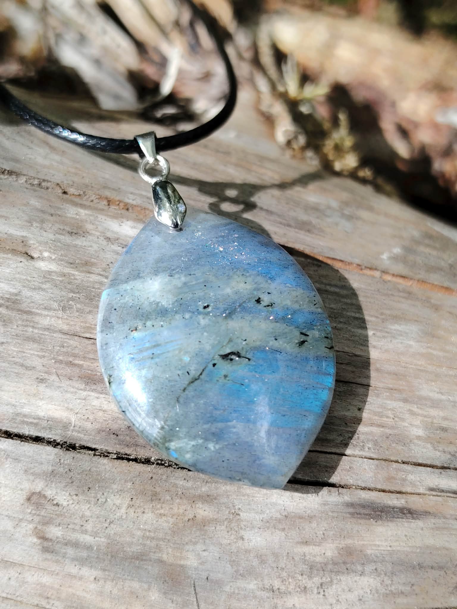Bijou labradorite marquise sur bois en lumière naturelle, reflets bleu gris et aspect poli pour clarté intérieure.