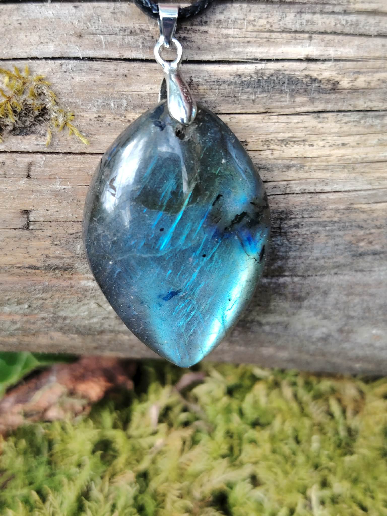 Pendentif labradorite marquise aux reflets bleus sur bois et mousse en décor naturel breton, bijou minéral pour intuition.