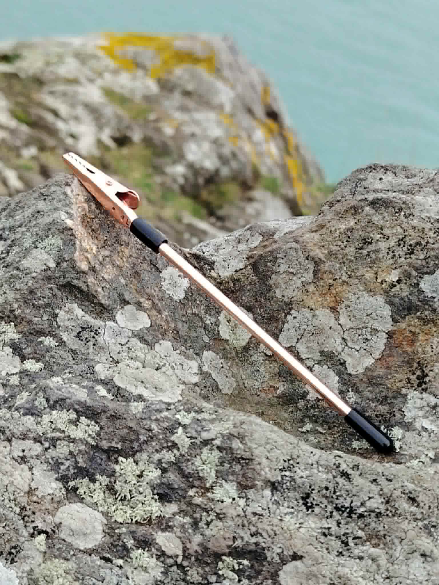 Aide fermoir pour bracelet rose doré posé sur roche en bord de mer breton, accessoire pratique pour attacher ses bijoux seule.