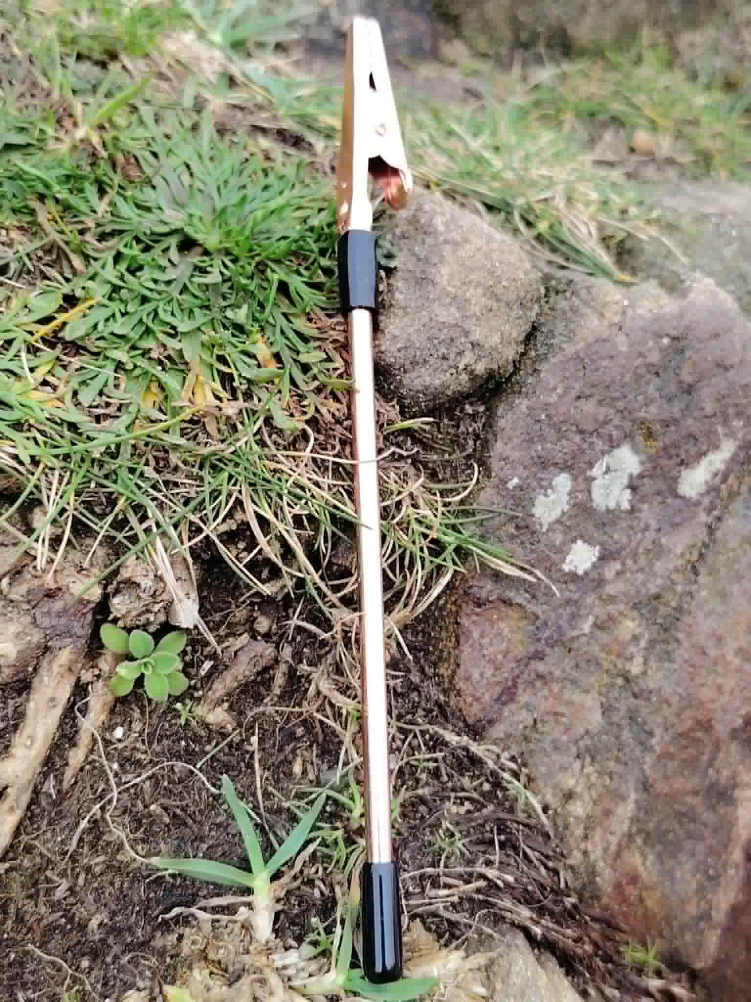 Aide fermoir rose doré avec embouts noirs détouré sur fond blanc, petit outil pour fermer les bracelets facilement.