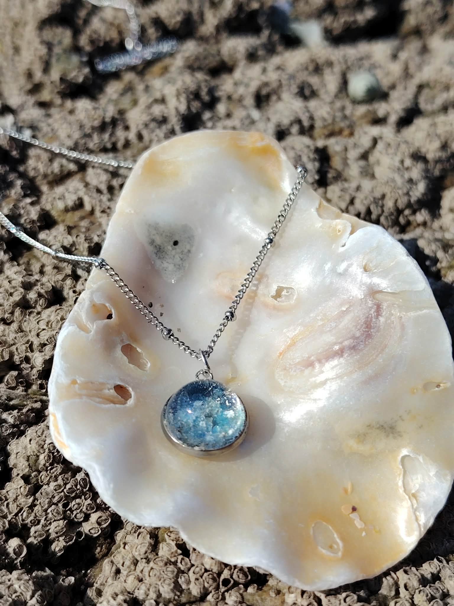 Collier Apatite en paillettes sur roche naturelle, pendentif rond argenté aux reflets bleus cristallins.