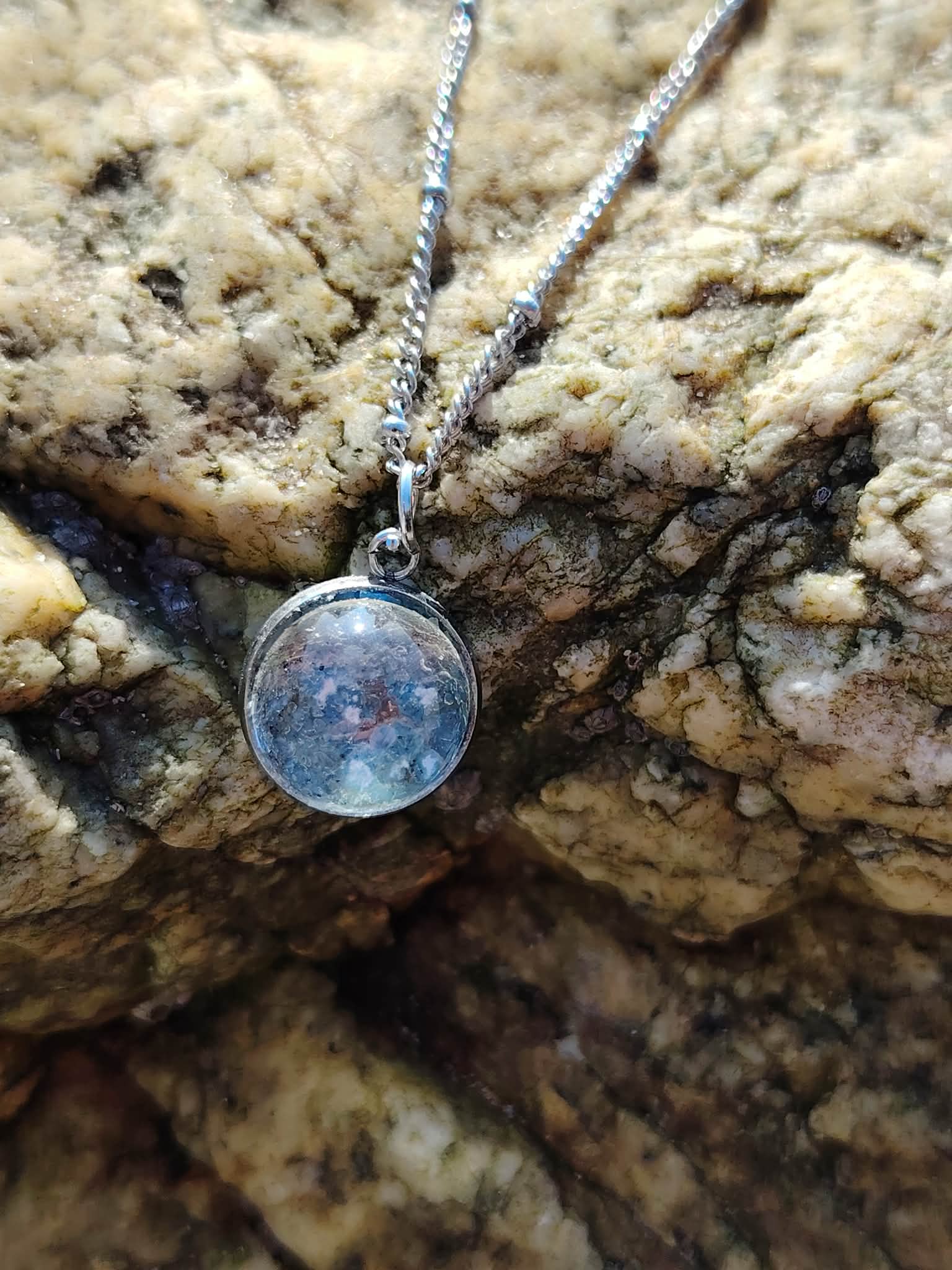 Collier Apatite en paillettes Création Magic Gaïa sur décor naturel breton, pendentif bleu argenté avec chaîne inox.