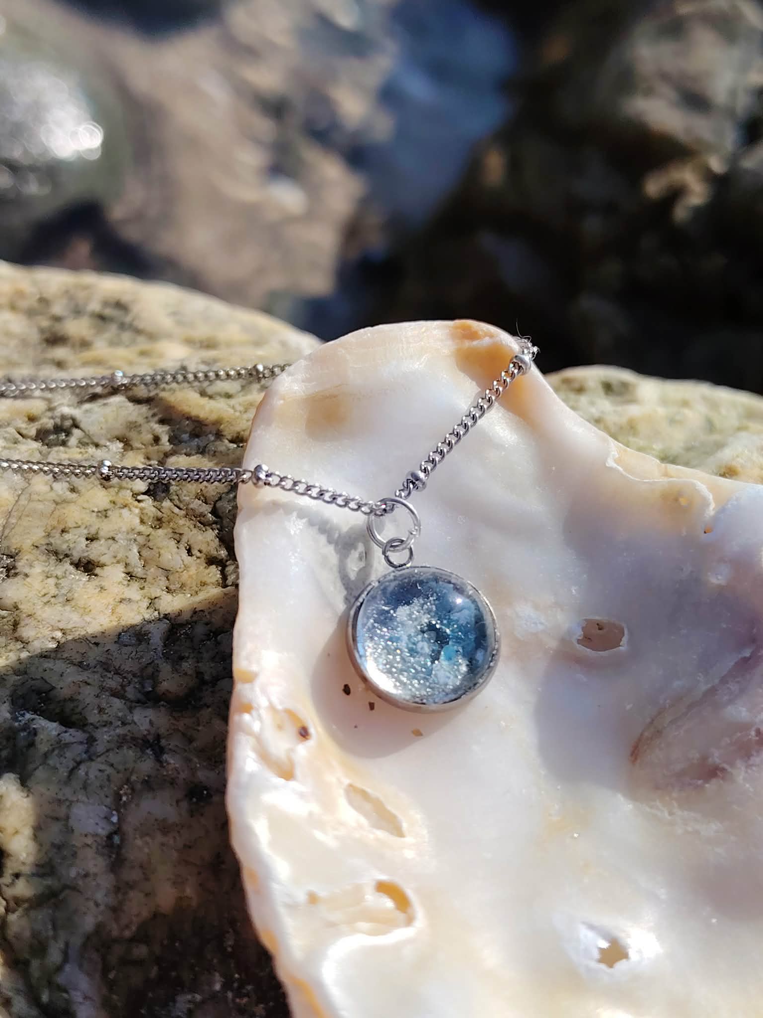 Pendentif Apatite bleu pailleté en gros plan, création Magic Gaïa avec cabochon argenté et chaîne inox.