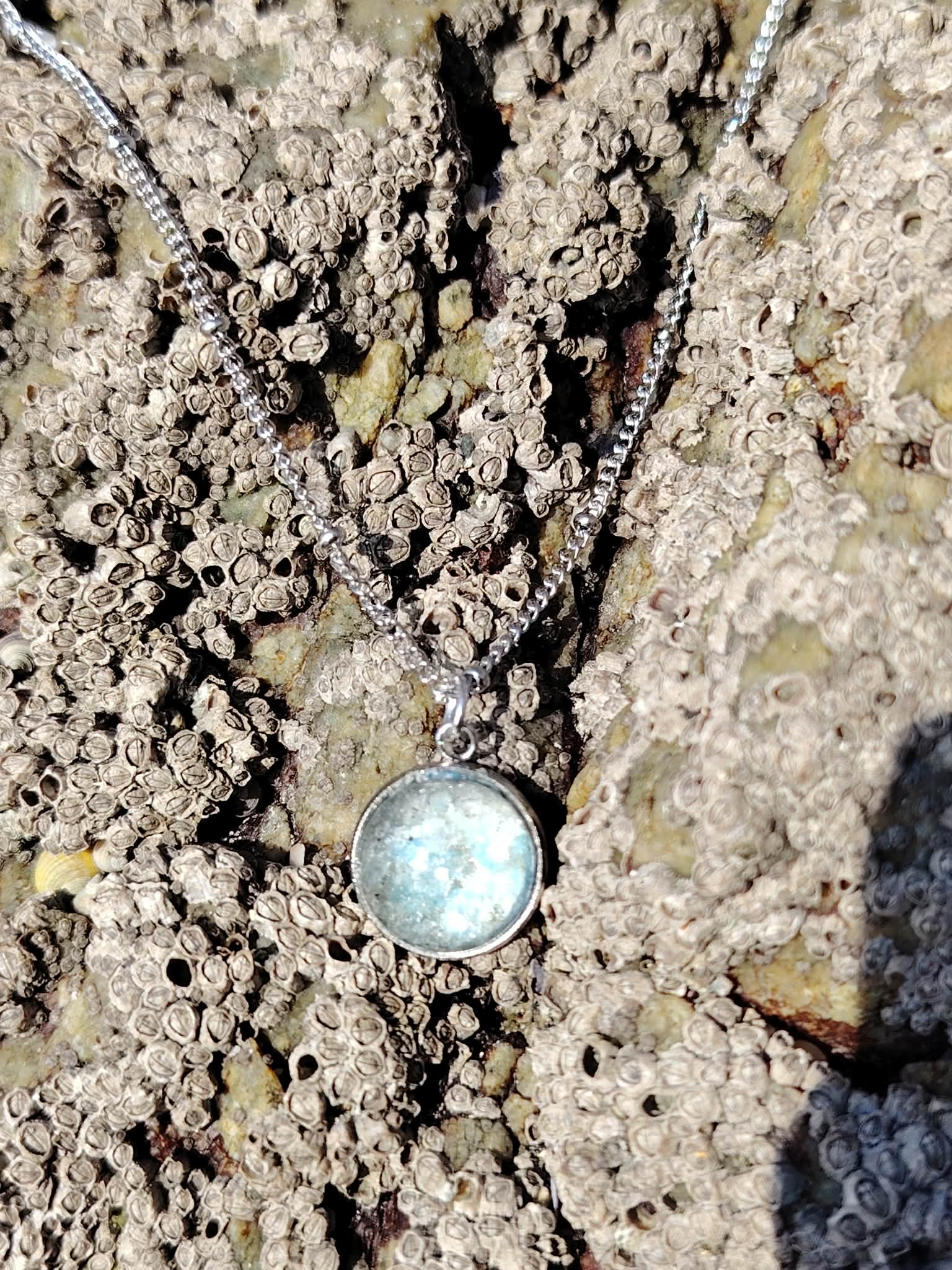 Collier Apatite en paillettes sur roche claire en bord de mer, pendentif bleu givré avec chaîne acier inoxydable.