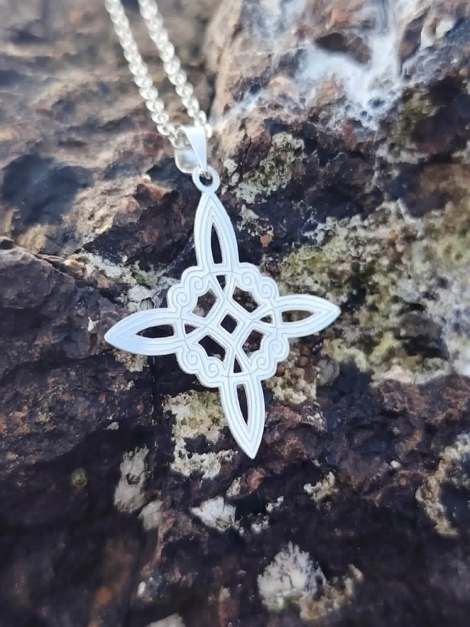 Bijou Nœud de Sorcière en argent 925 sur roche sombre, pendentif ajouré aux détails délicats et mystiques.