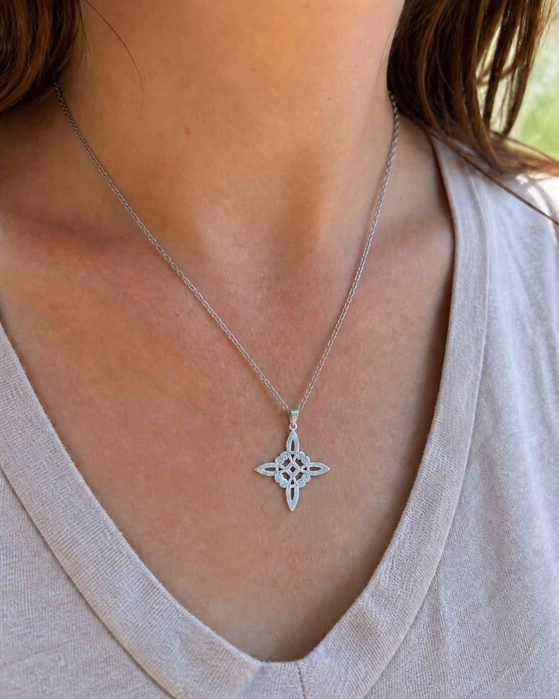 Pendentif Nœud de Sorcière porté au cou sur chaîne argentée, bijou discret en argent 925 avec haut clair.