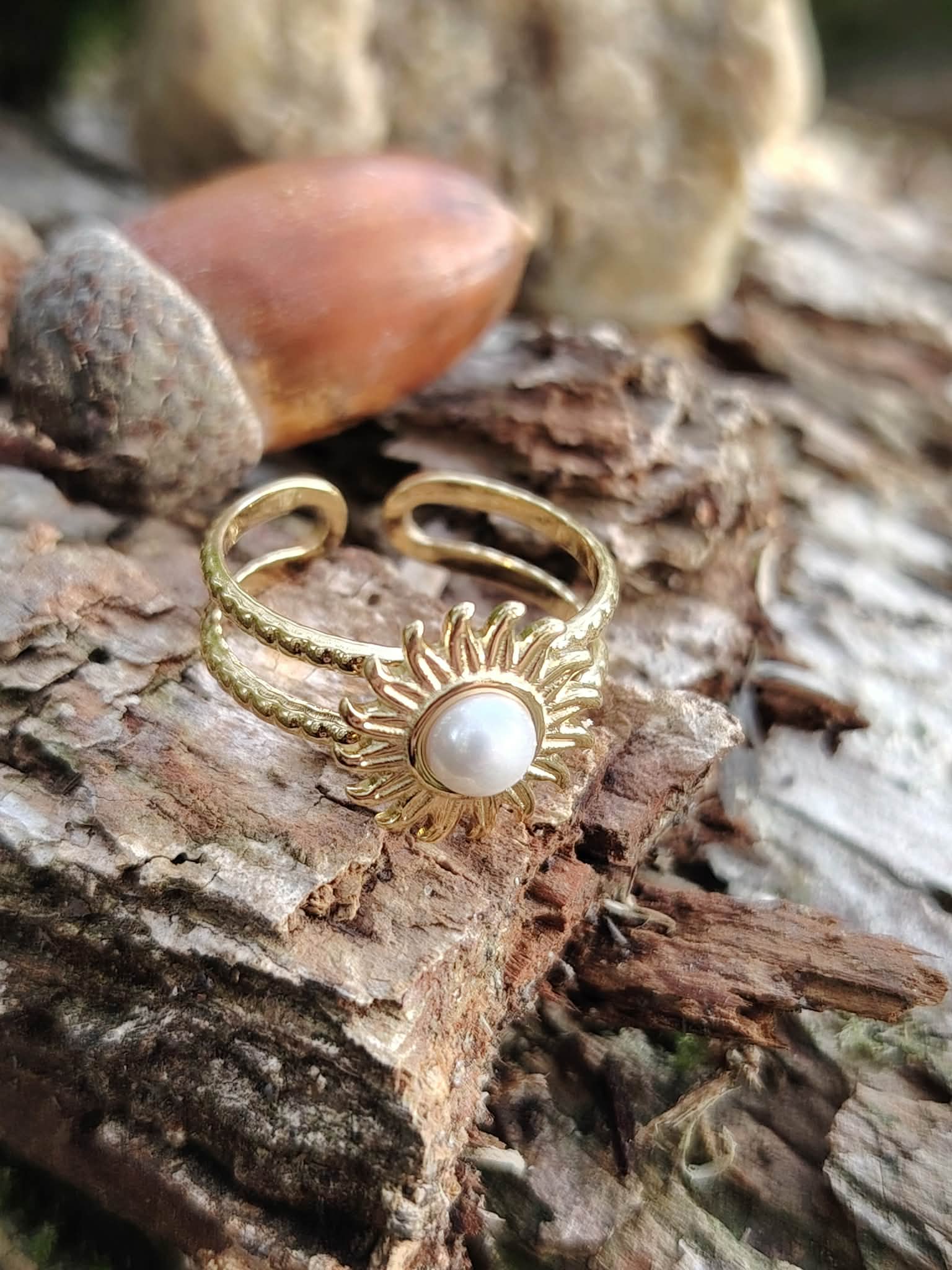 Bague dorée ajustable sur écorce naturelle, soleil travaillé avec cabochon blanc nacré au centre.