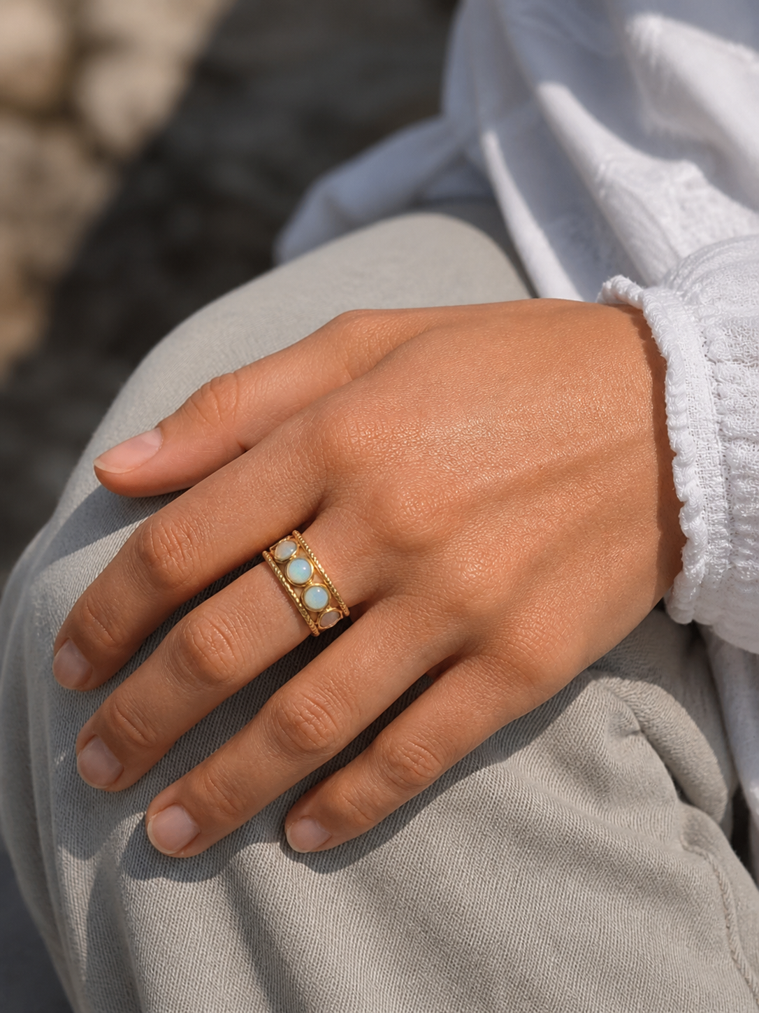 Bague multi Amazonite portée à la main en lumière naturelle, anneau doré réglable et pierres bleu-vert pour douceur et harmonie.