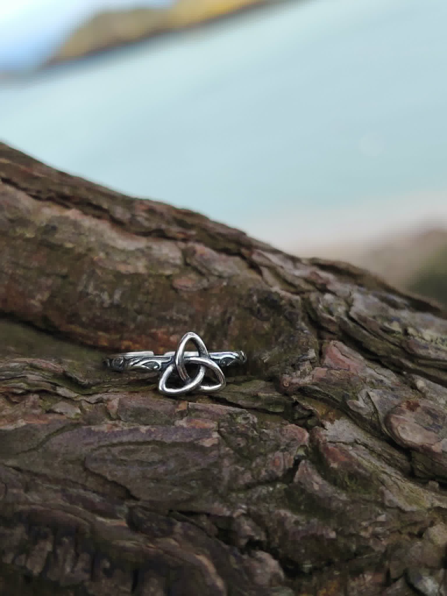 Bague Triquetra Argent 925 sur bois face à la mer, motif entrelacé fin et anneau travaillé pour un style celtique discret.