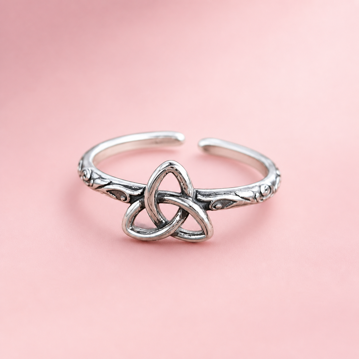 Bague Triquetra en argent 925 détourée sur fond rosé doux, anneau ajustable travaillé et symbole entrelacé au style celtique élégant.