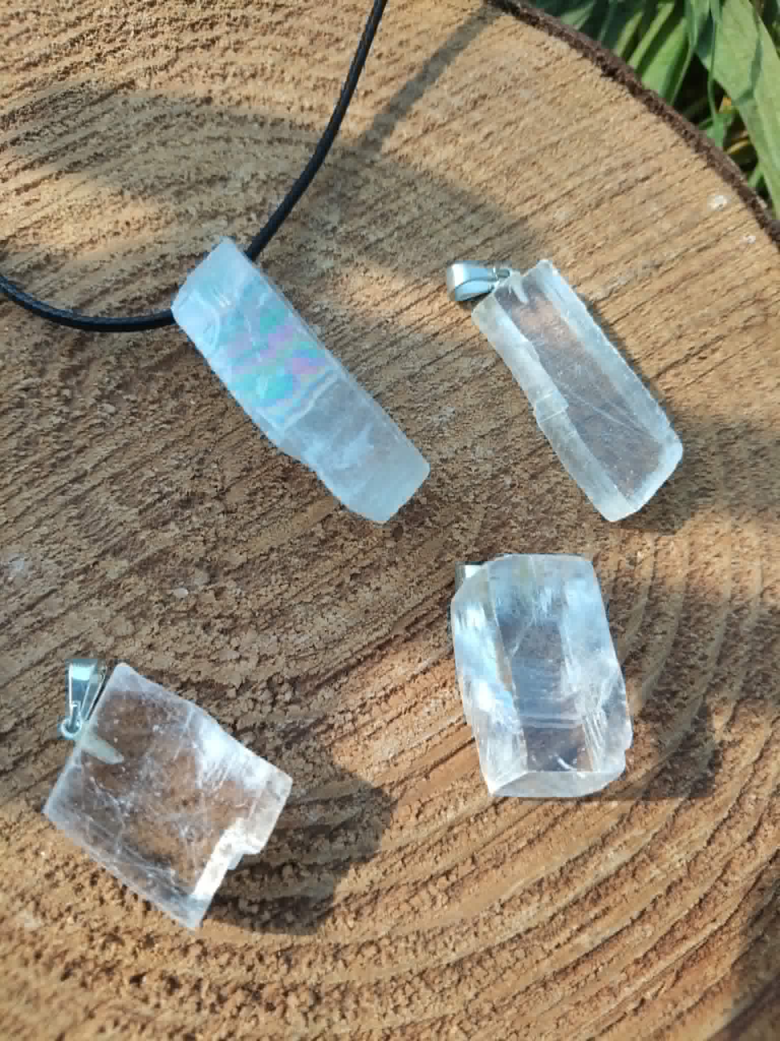 Lot de pendentifs Calcite Optique sur bois naturel, pierres translucides aux voiles internes pour perception subtile et harmonie spirituelle.