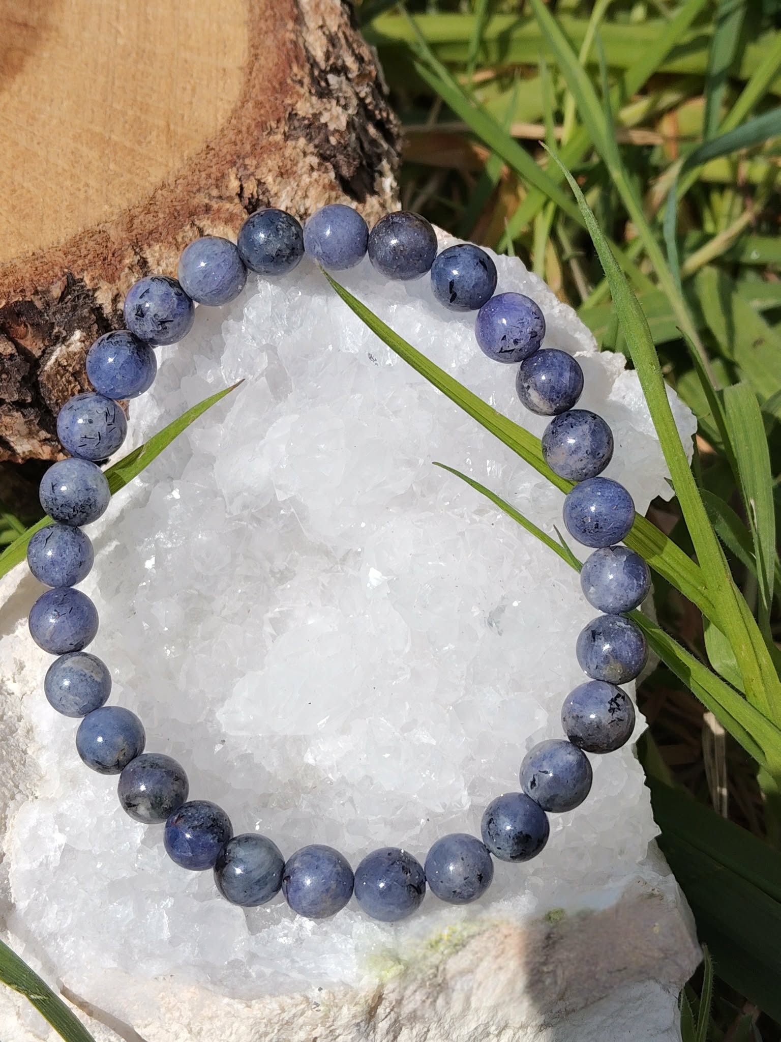 Bracelet Tanzanite sur cristal blanc et herbe verte, perles violet bleuté pour méditation, clairvoyance et éveil intérieur.