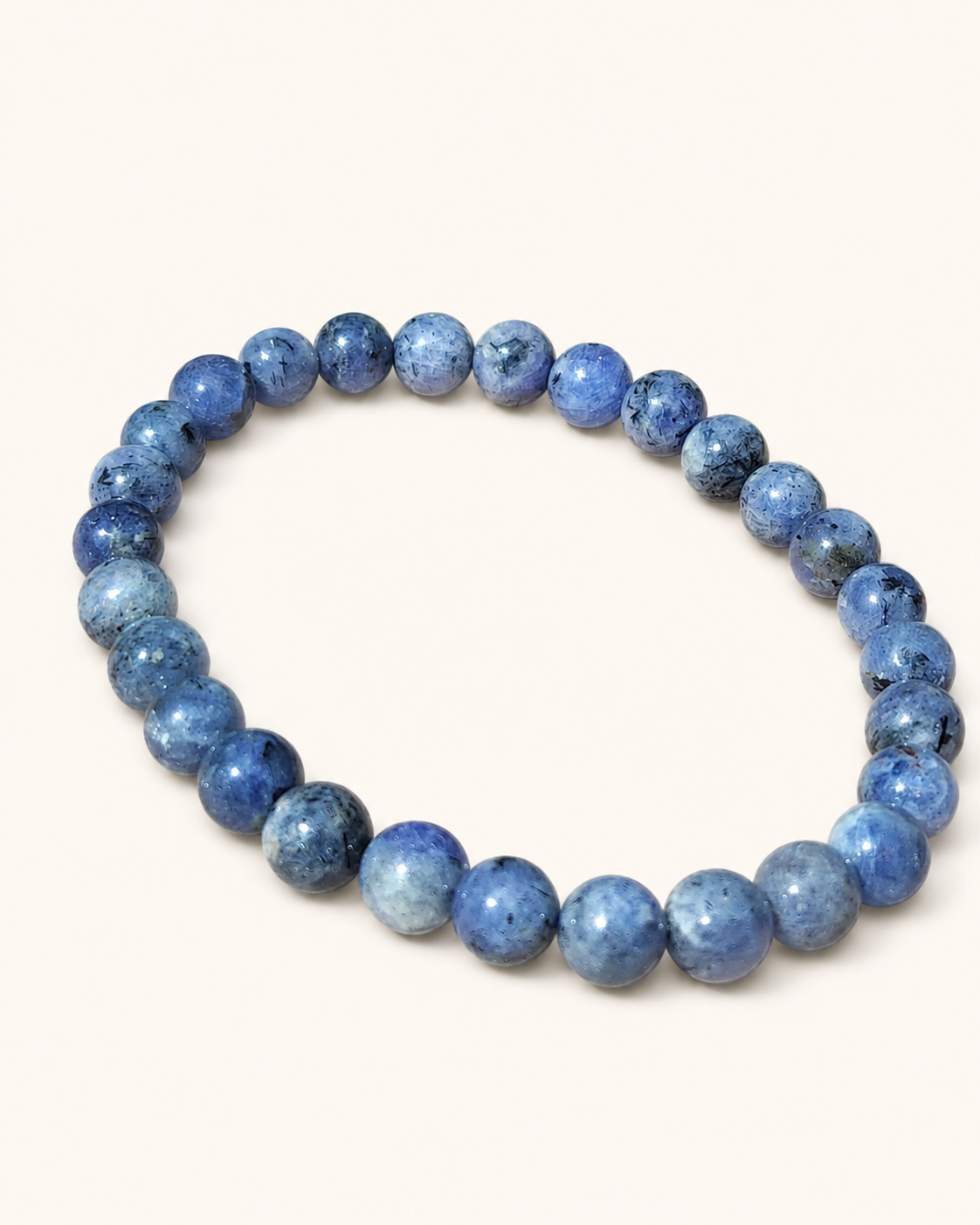Bracelet Tanzanite 6-7 mm détouré sur fond clair, perles bleues polies aux inclusions naturelles, intuition, créativité et parole alignée.