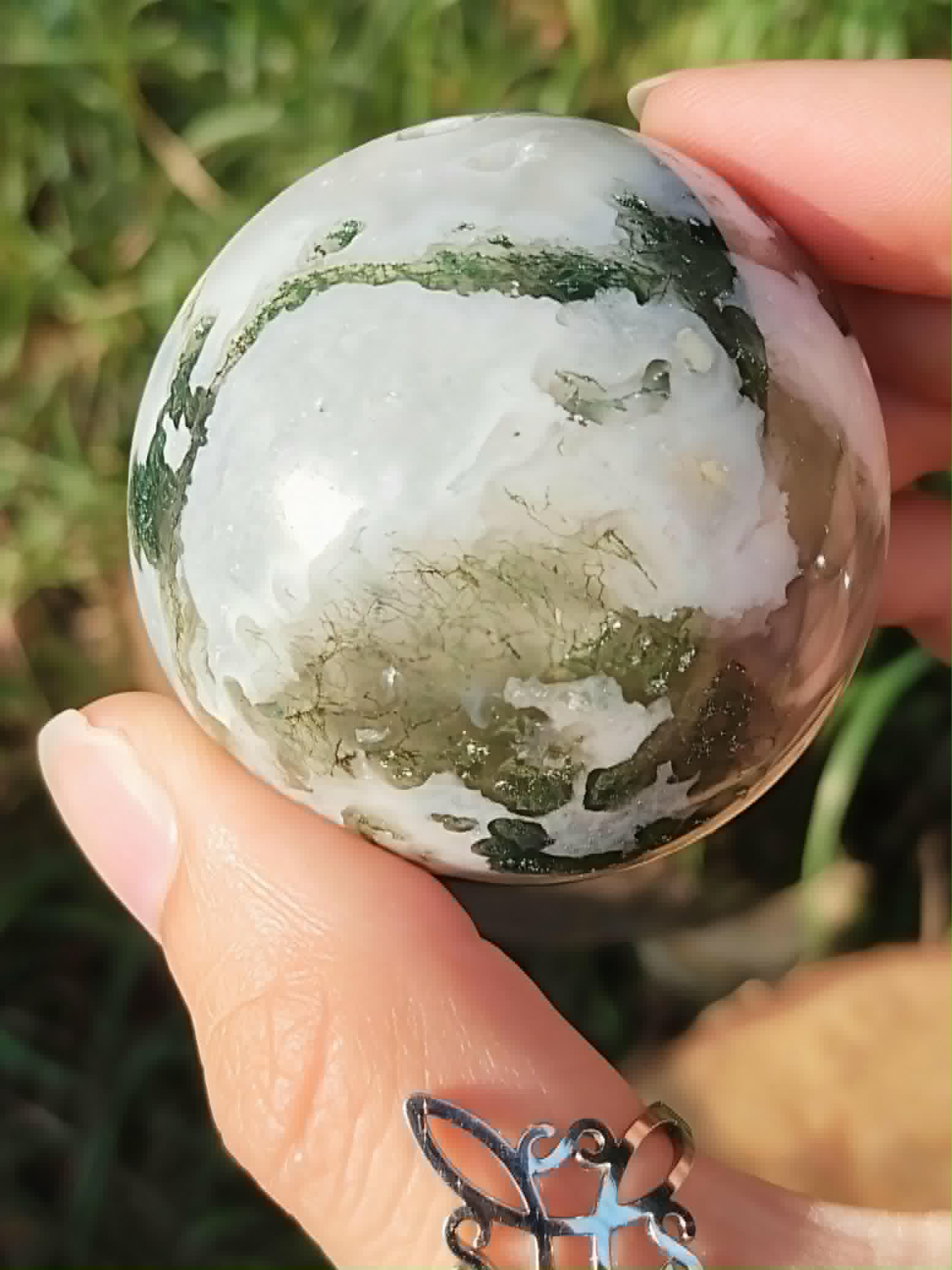 Agate Arbre tenue entre les doigts, détails translucides et inclusions vertes évoquant croissance intérieure.