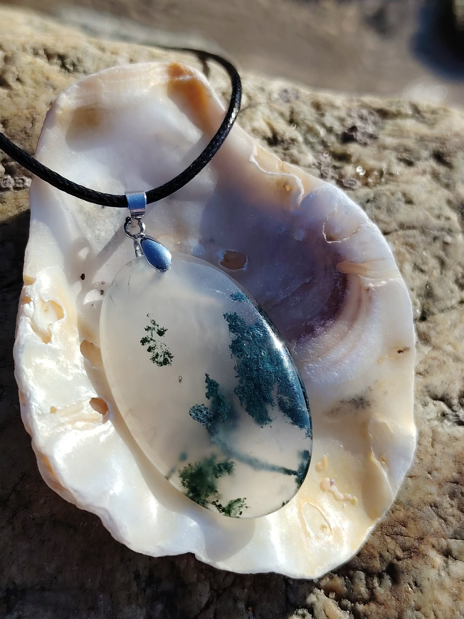 Pendentif Agate Mousse sur coquillage en Bretagne, cordon noir et inclusions vertes pour un bijou naturel apaisant.