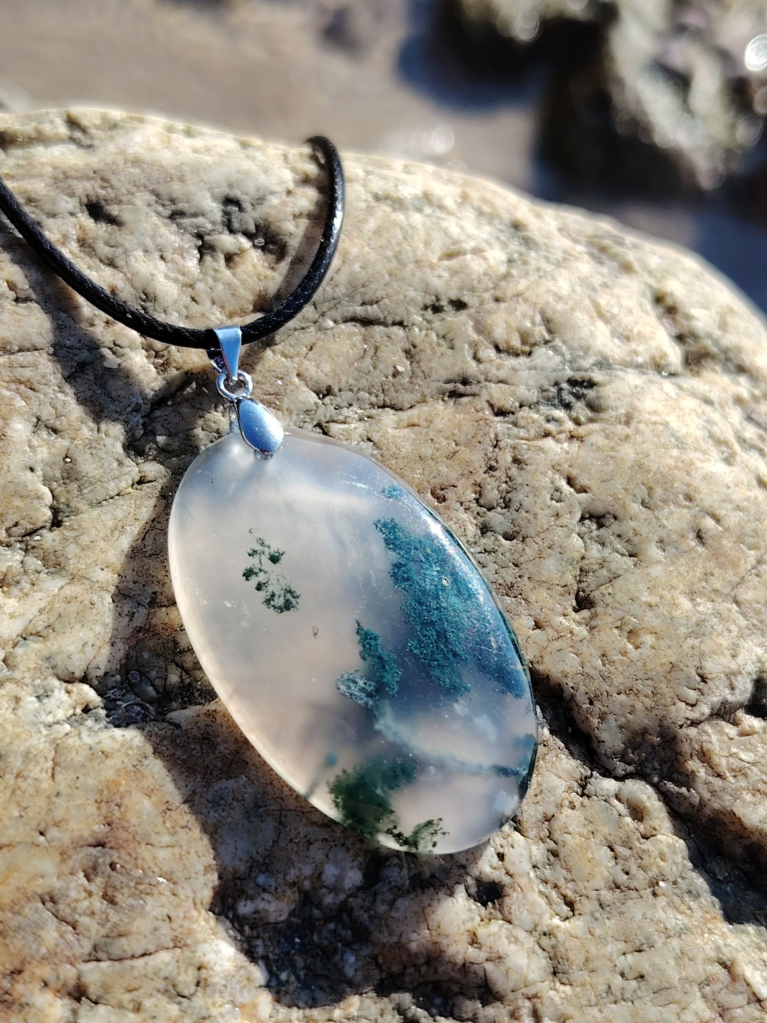 Pendentif ovale en Agate Mousse sur rocher clair breton, cordon noir et reflets verts pour une allure nature.