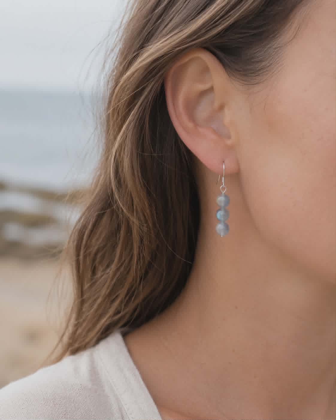 Boucles d’oreilles Labradorite Magic Gaïa portées en bord de mer, trois perles rondes bleu gris, intuition douce.