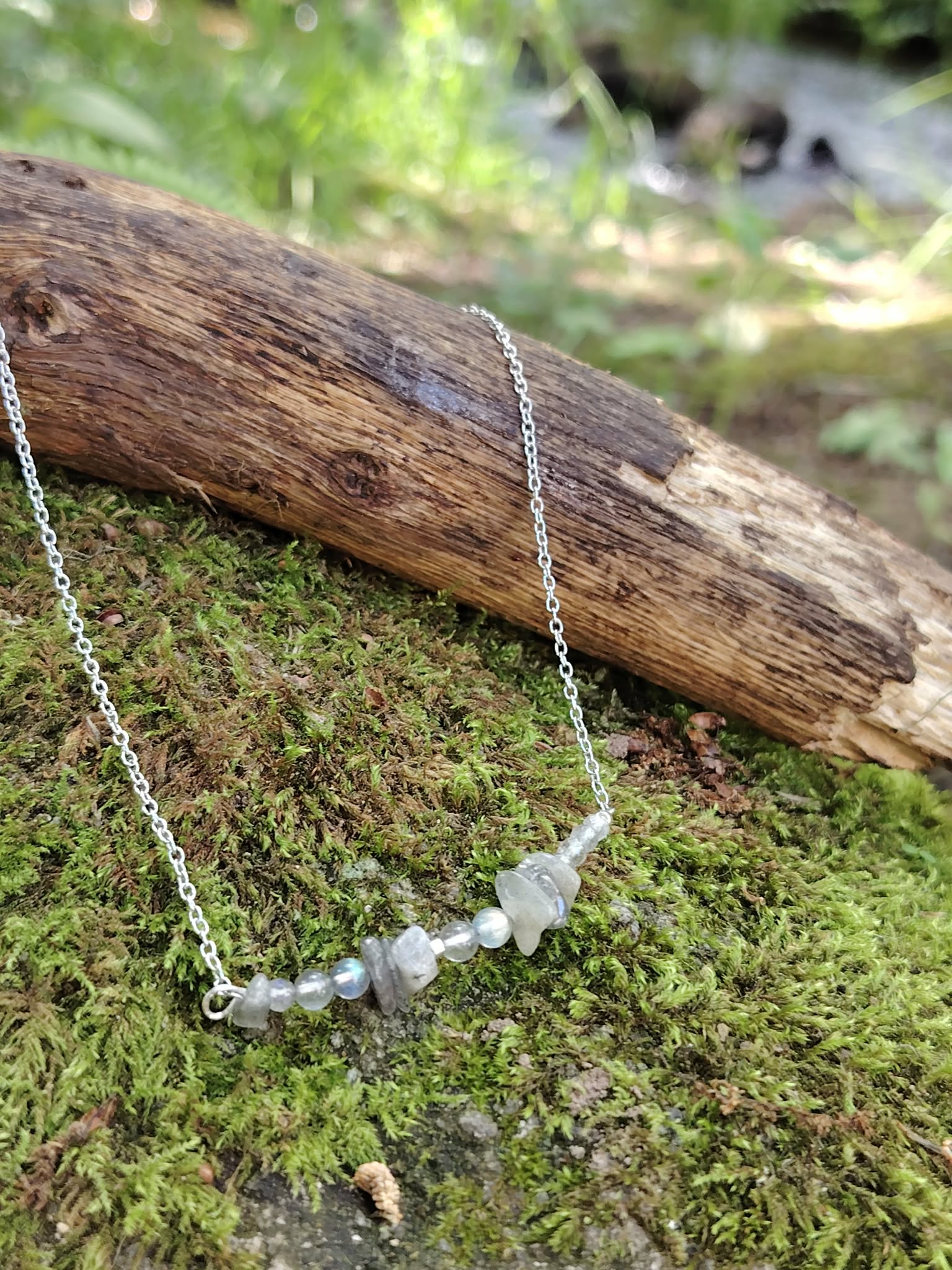 Collier Labradorite posé sur mousse verte près d’un ruisseau, création Magic Gaïa fine et naturelle.