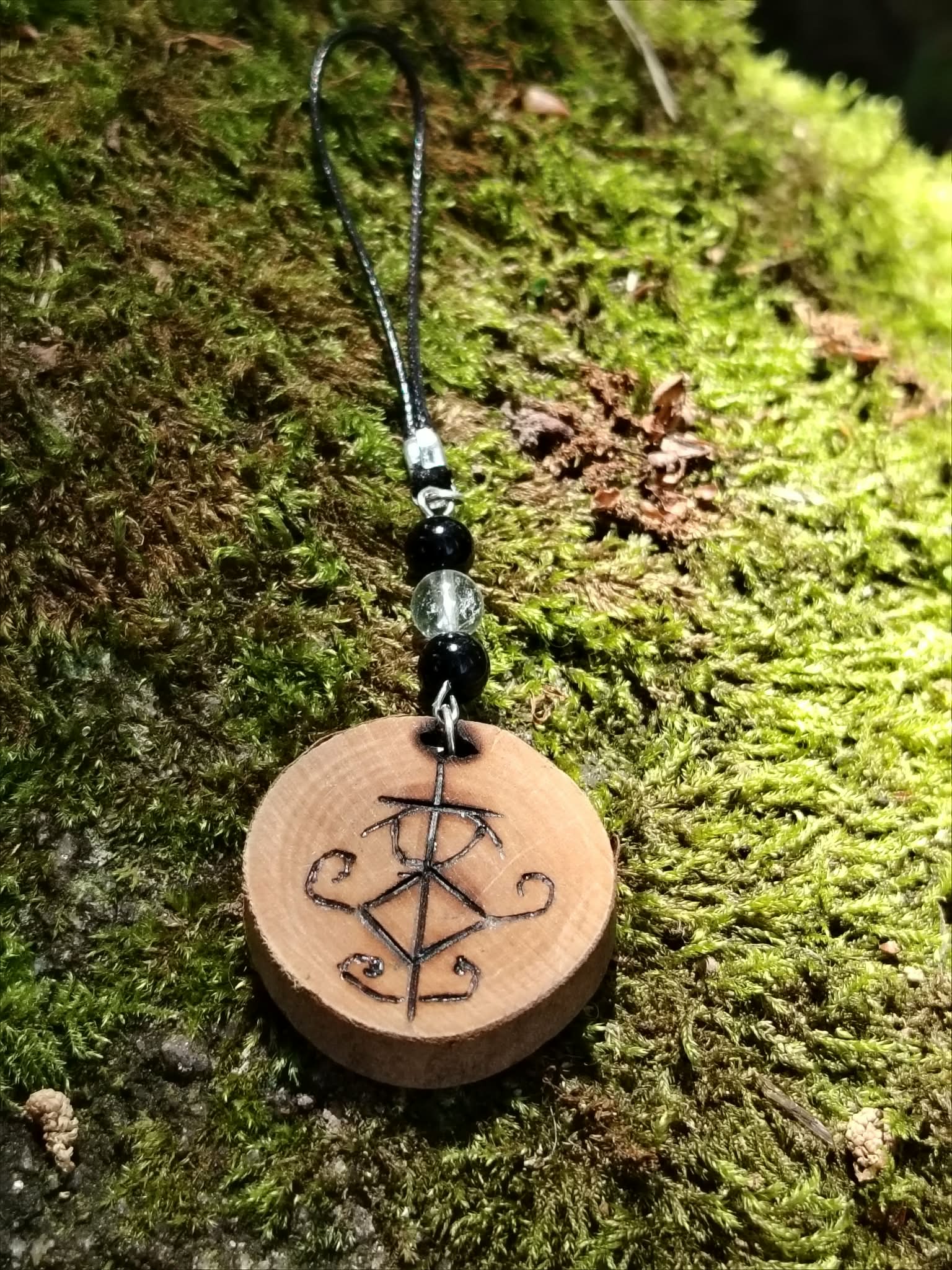 Création Magic Gaïa bijou de téléphone bois avec sigil protecteur, perles de tourmaline noire et cristal de roche.