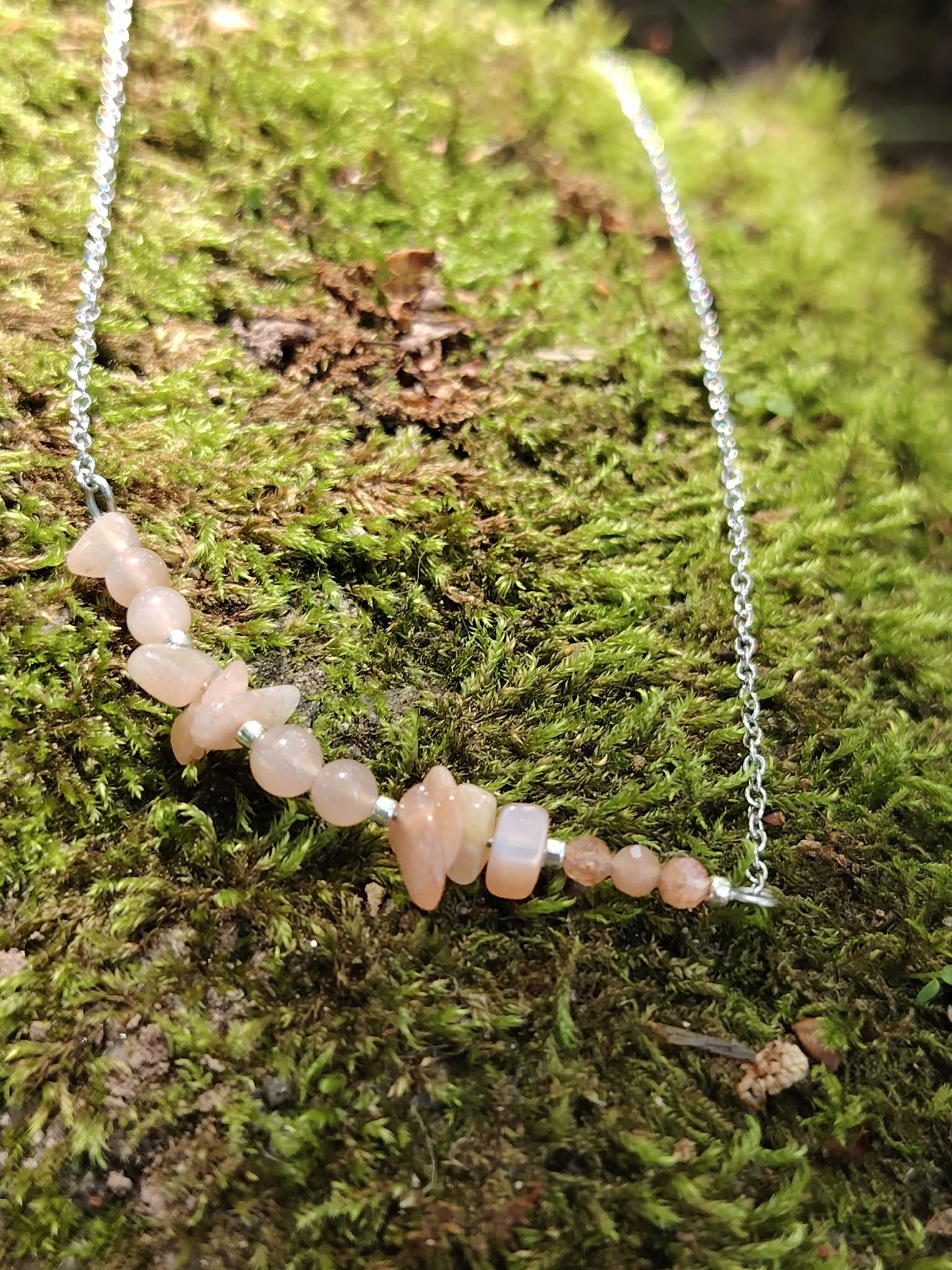 Collier pierre de soleil création Magic Gaïa en situation naturelle, pierres pêche lumineuses sur chaîne acier, énergie solaire et confiance.