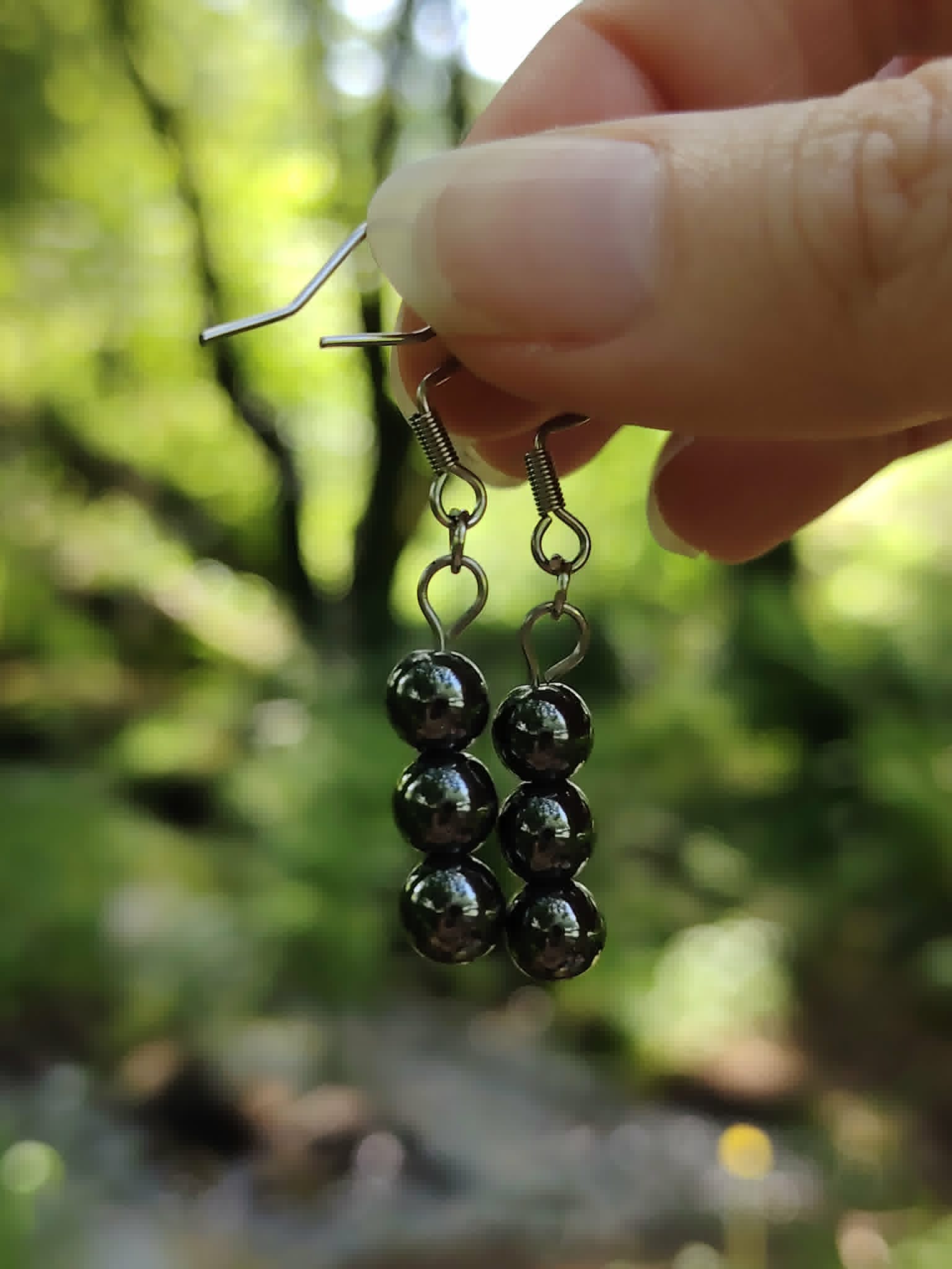 Boucles d’oreilles hématite création Magic Gaïa tenues en forêt, perles métalliques brillantes, ancrage et protection.