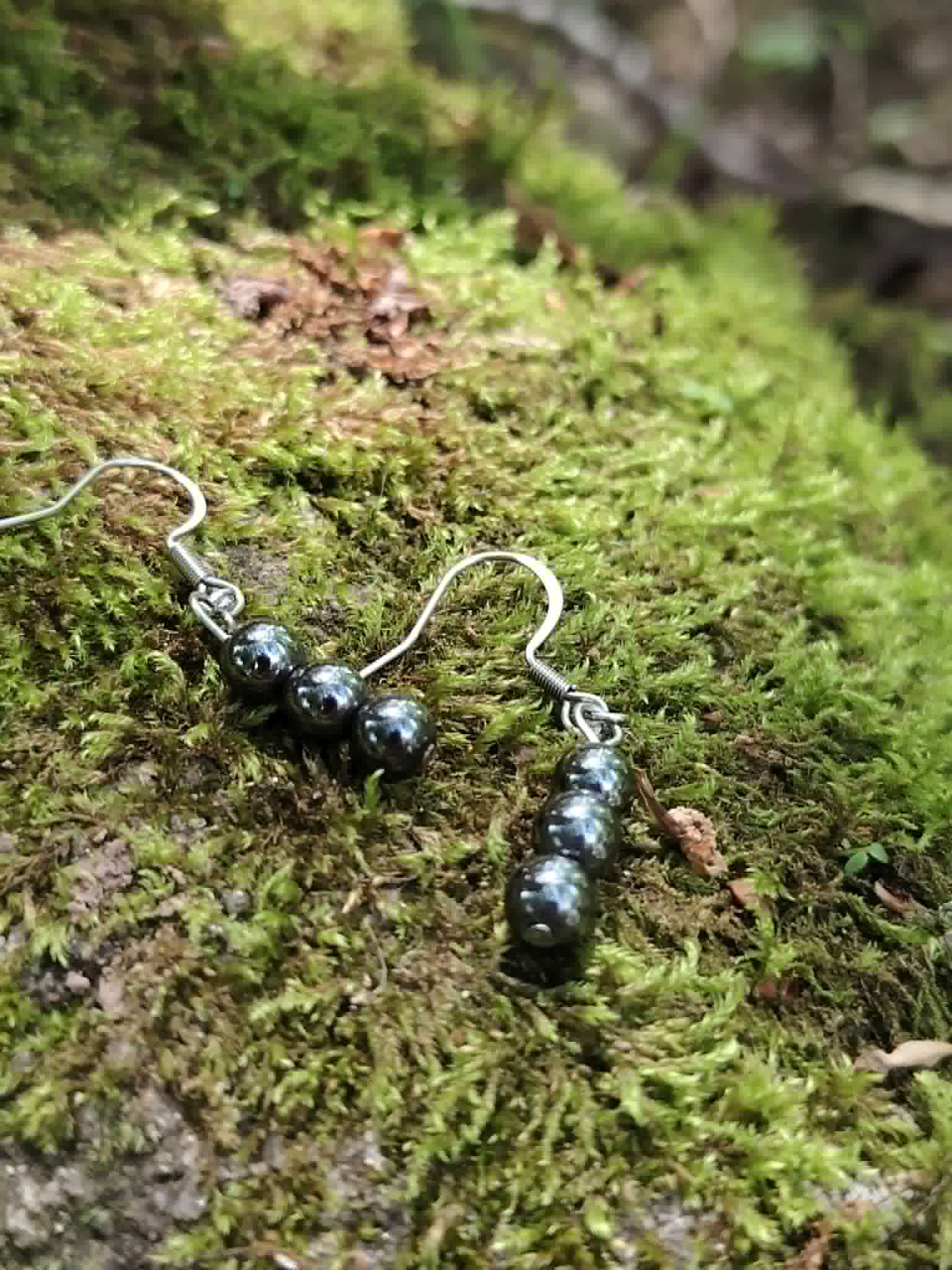 Boucles d’oreilles hématite création Magic Gaïa posées dans la mousse, crochets argentés, recentrage et équilibre.