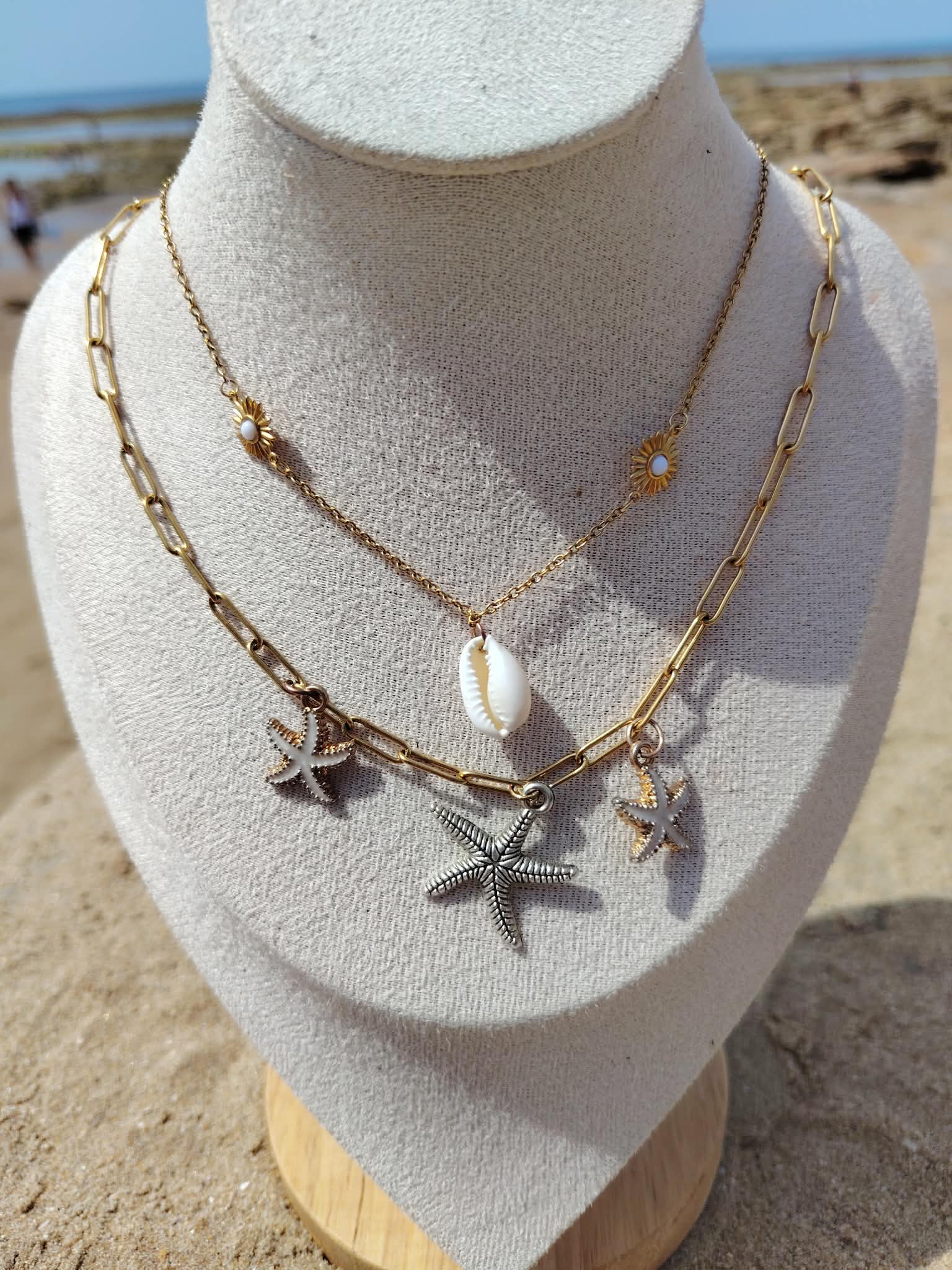 Collier double rang étoiles de mer doré sur buste beige, plage de Vendée en arrière-plan