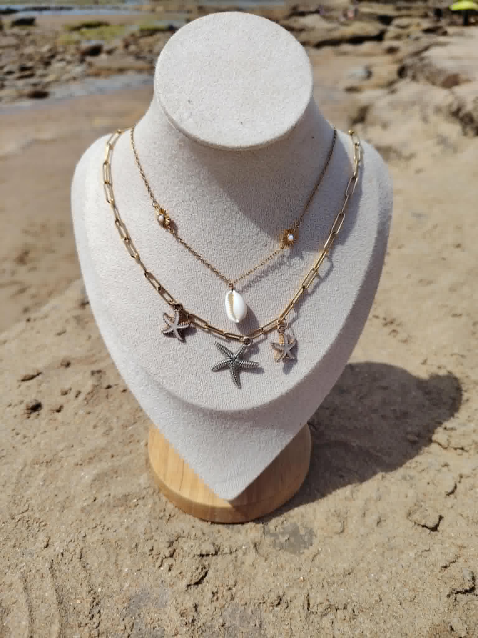 Collier marin double rang doré présenté sur buste beige au bord de la mer en Vendée