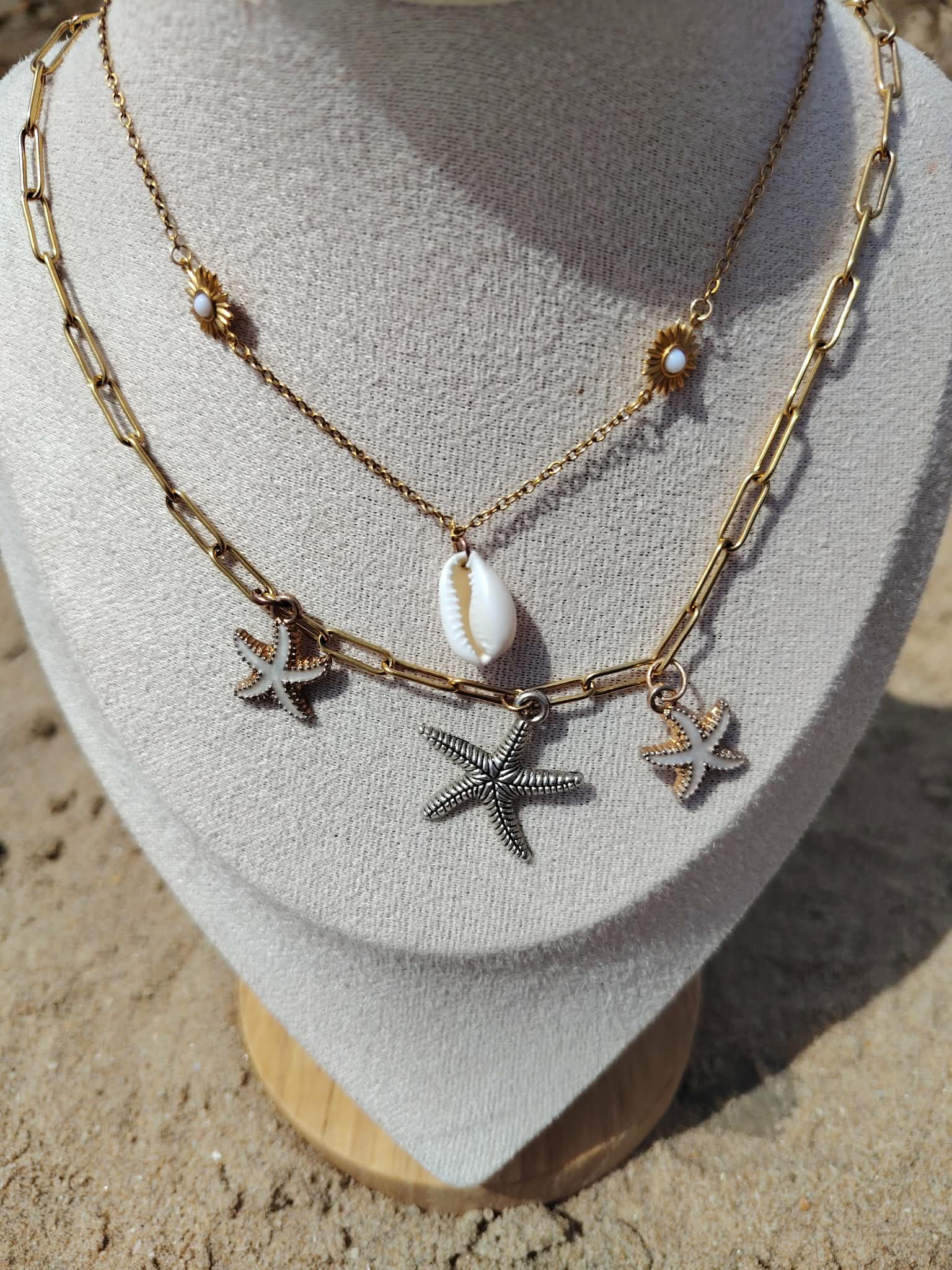 Création Magic Gaïa, collier double rang étoiles de mer doré avec perle blanche sur buste beige en extérieur