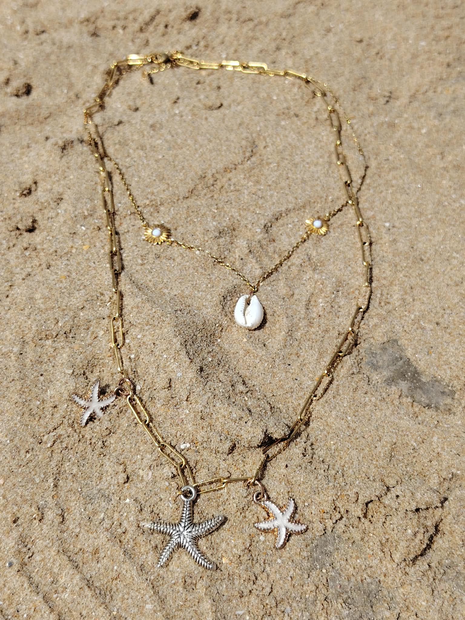 Création Magic Gaïa, collier double rang étoiles de mer doré posé sur le sable en Vendée