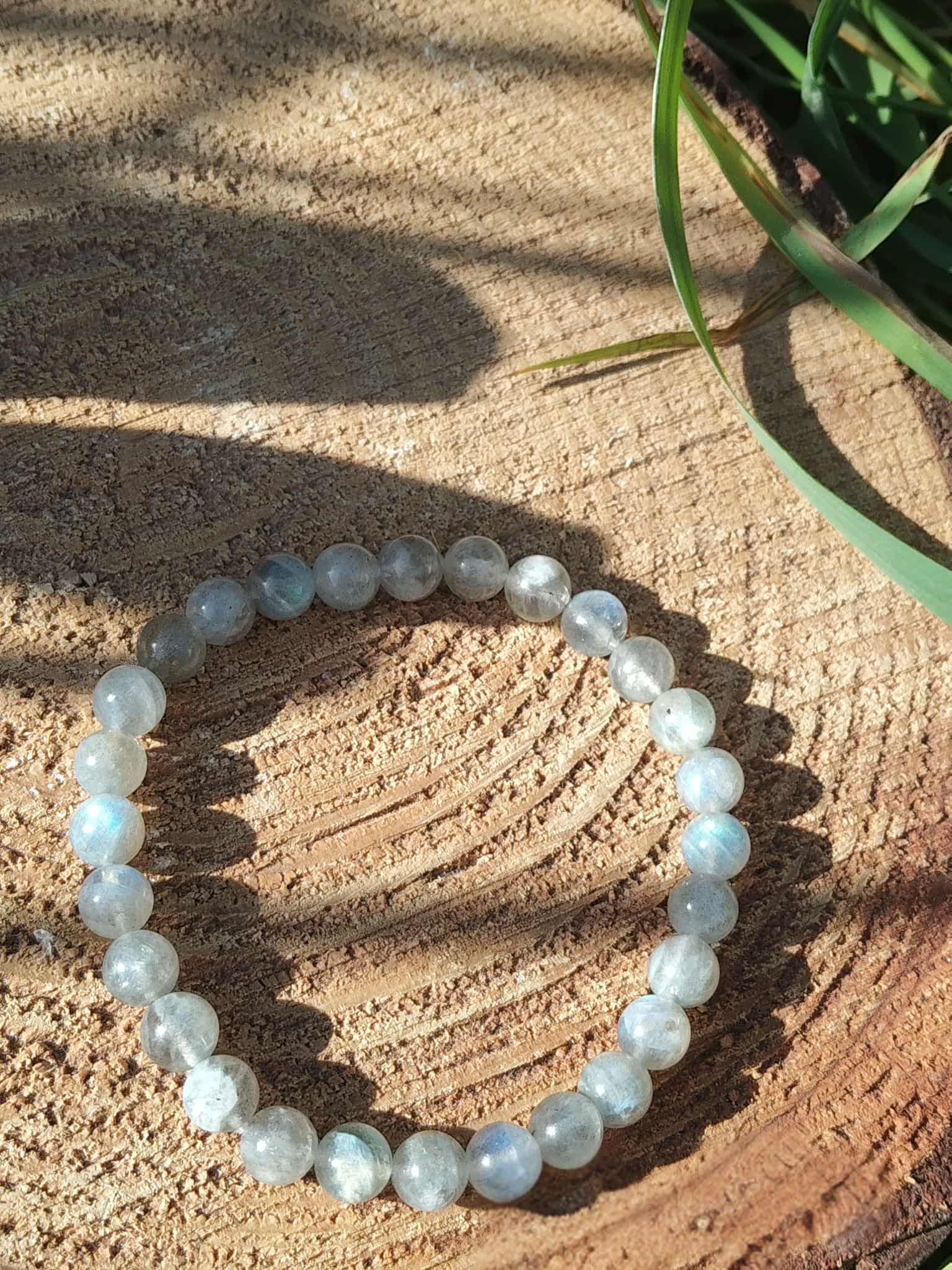Bracelet labradorite gris bleuté sur rondin de bois, reflets subtils et énergie douce, apaisement et recentrage
