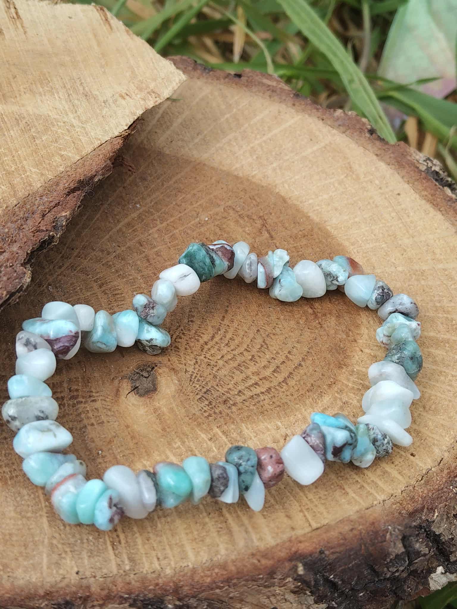Bracelet larimar baroque sur tranche de bois naturel avec feuillage vert, éclats bleu ciel, blanc et brun marbré pour apaisement du ressenti et fluidité émotionnelle