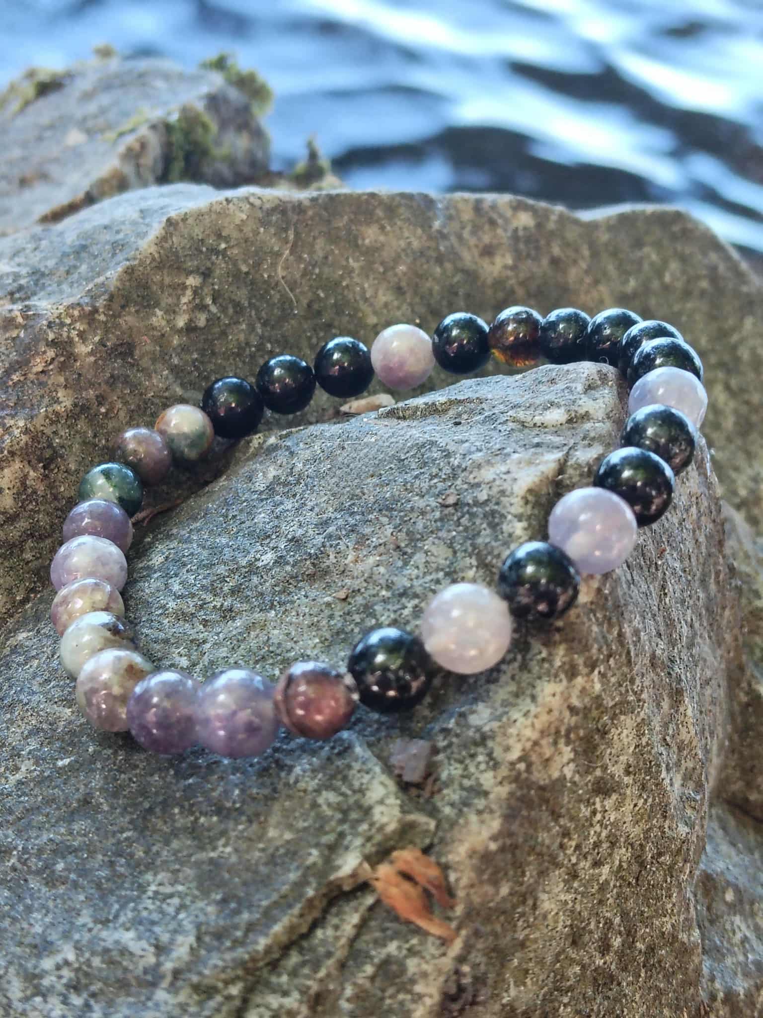 Bracelet tourmaline multicolore 6 mm sur rocher près de l’eau, bijou en pierre naturelle pour ancrage profond et sécurité énergétique