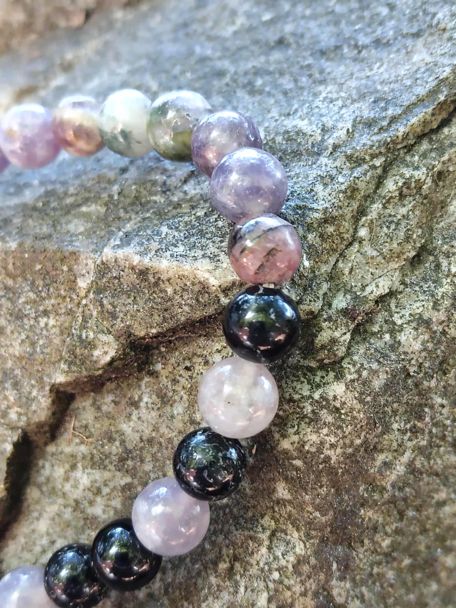 Gros plan bracelet tourmaline multicolore 6 mm sur rocher, nuances naturelles et reflets variés pour équilibre émotionnel et enracinement