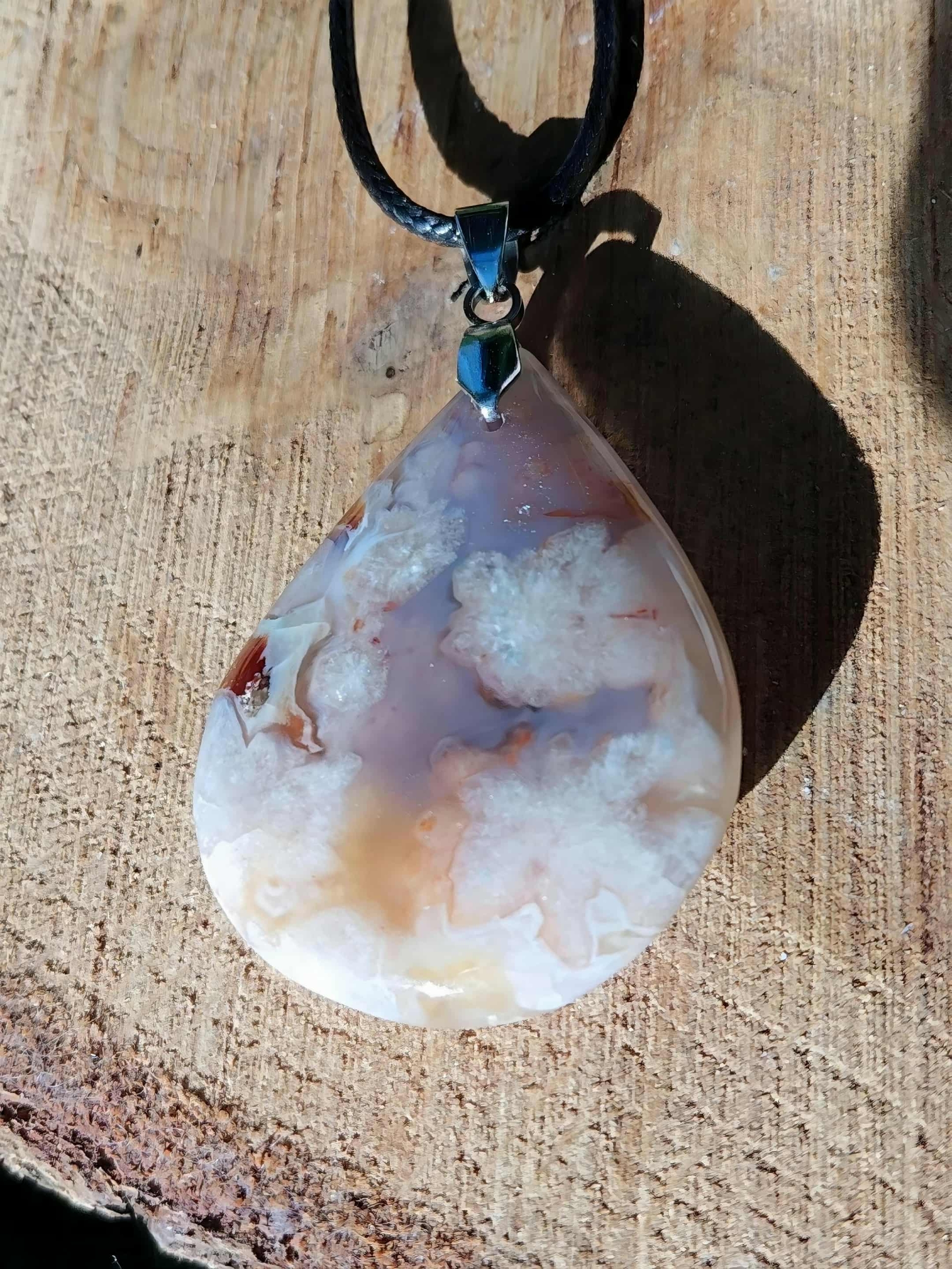 Pendentif agate fleur de cerisier en goutte, posé sur rondin de bois, teintes crème-rose, douceur et sérénité