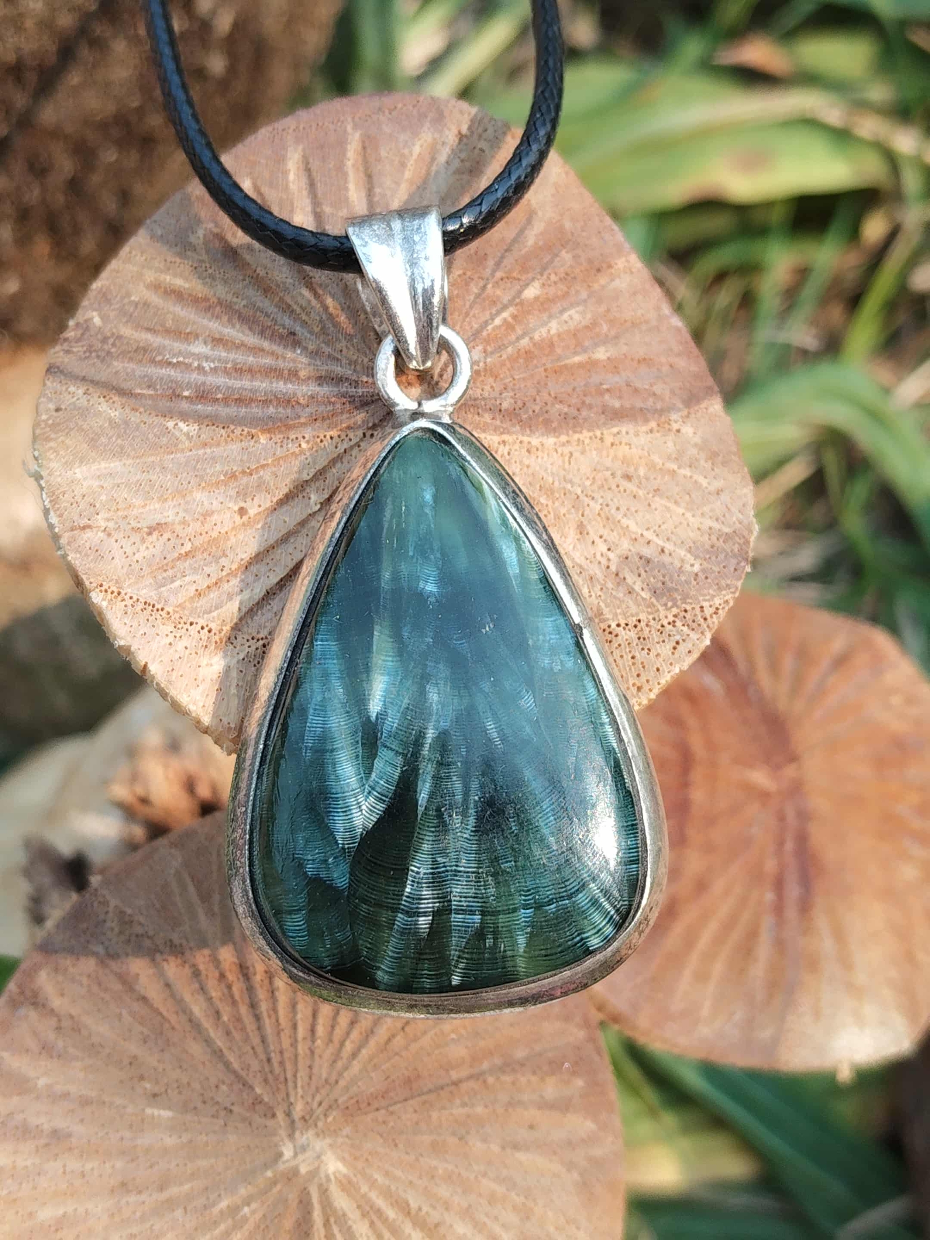 Collier pendentif séraphinite fibreuse au chatoiement vert sur support bois, monture argent 925, bijou en pierre naturelle évoquant la tranquillité, la sensibilité apaisée et l’équilibre émotionnel.
