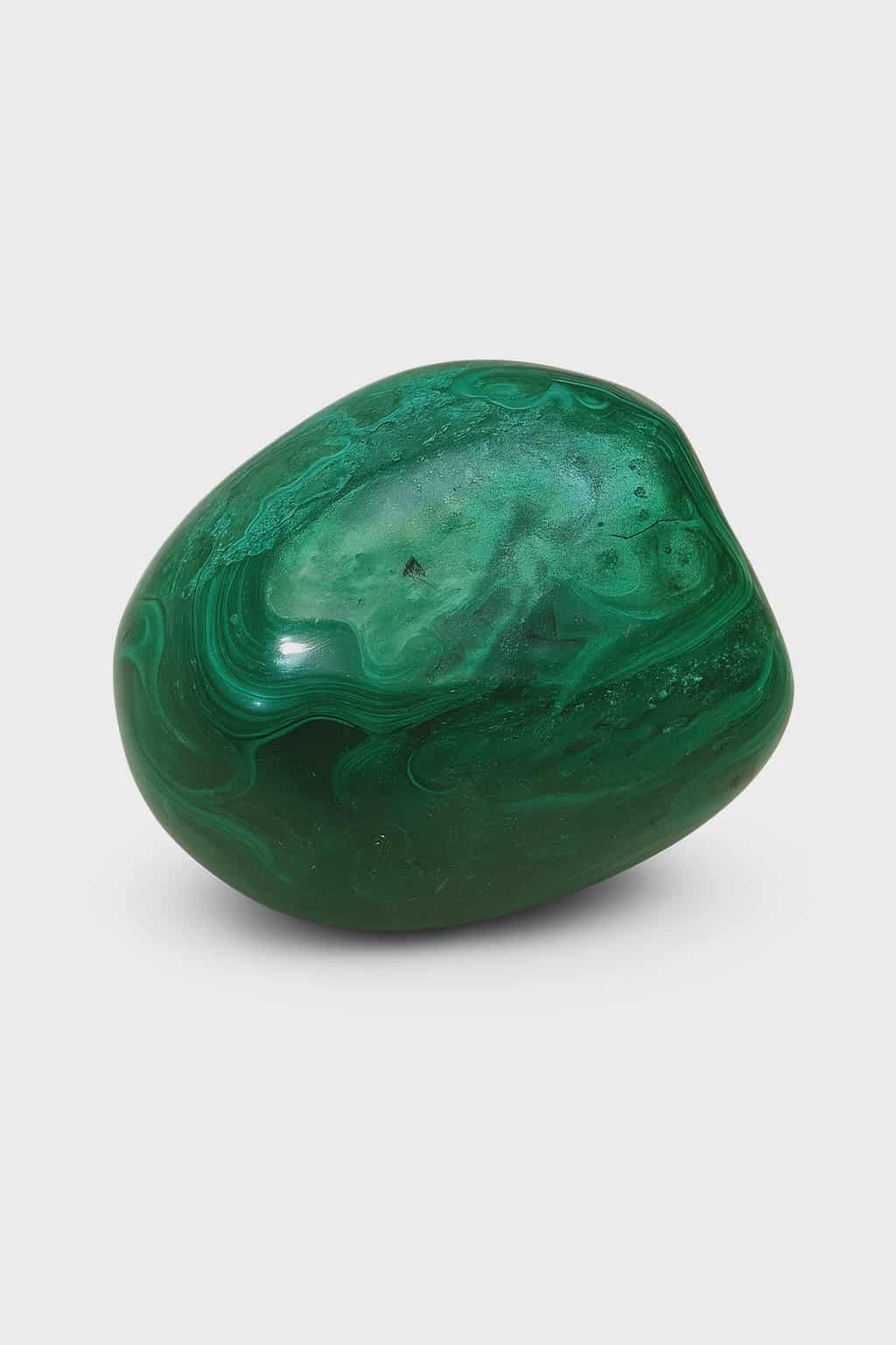 Pierre roulée en malachite verte veinée sur fond blanc, pierre de protection, d’ancrage et de transformation.