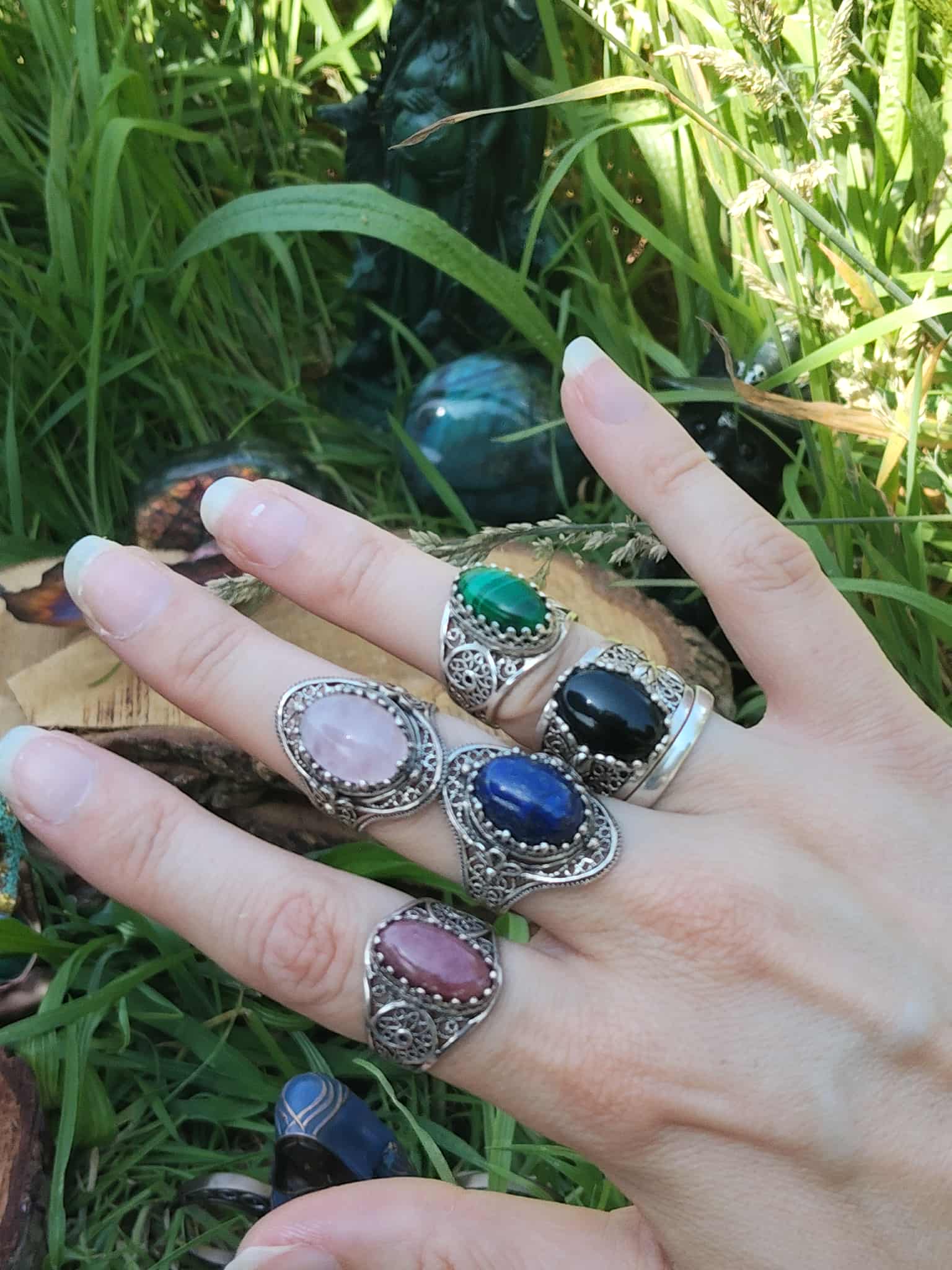 Main ornée de bagues artisanales en argent sterling 925 : cabochons de Malachite, Quartz Rose, Lapis-Lazuli, Rhodonite et Onyx, style filigrané, décor végétal