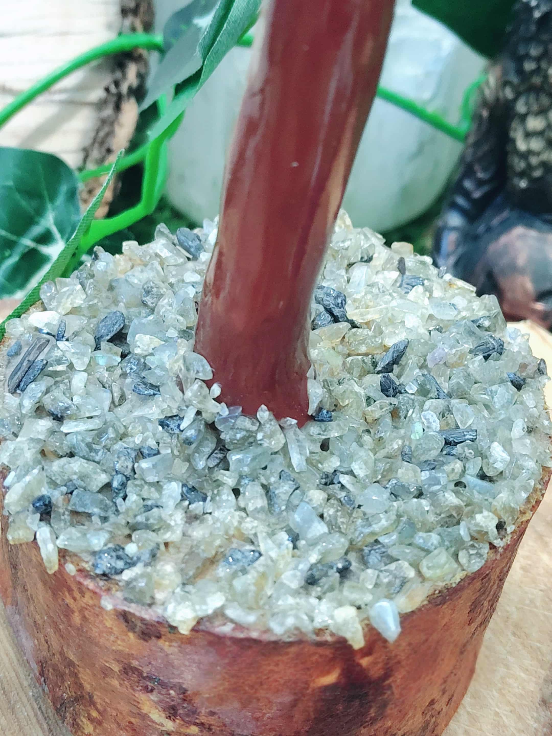 Gros plan sur la base d’un arbre de vie en labradorite en Bretagne, socle en bois et éclats minéraux polis, ancrage et clarté intérieure.