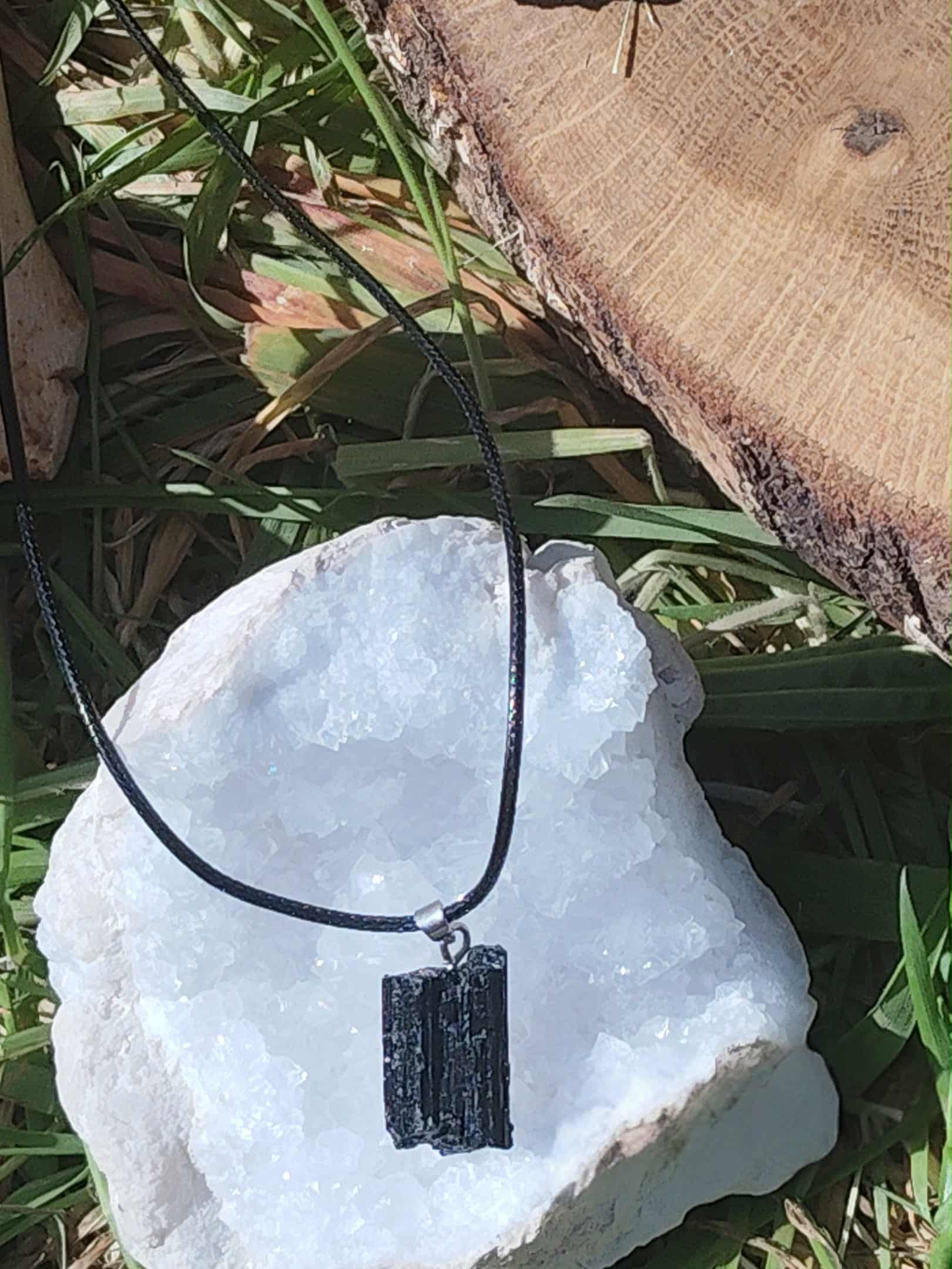 Pendentif tourmaline noire brute sur une géode blanche, pierre naturelle reliée à l’ancrage, à la purification énergétique et à la stabilité intérieure.