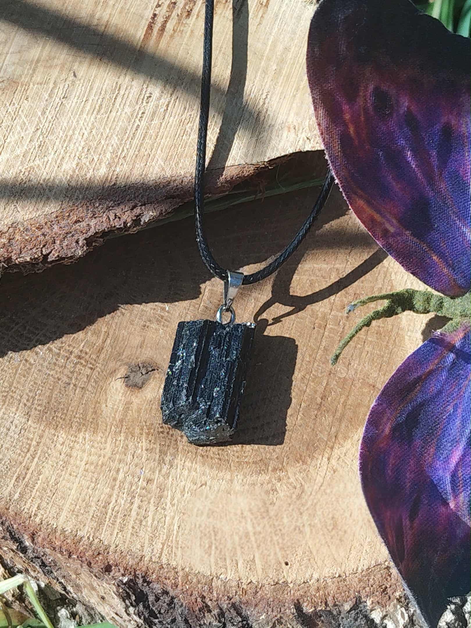Pendentif tourmaline noire brute sur bois naturel, bijou en pierre naturelle associé à l’ancrage, à la stabilité intérieure et à la protection subtile.