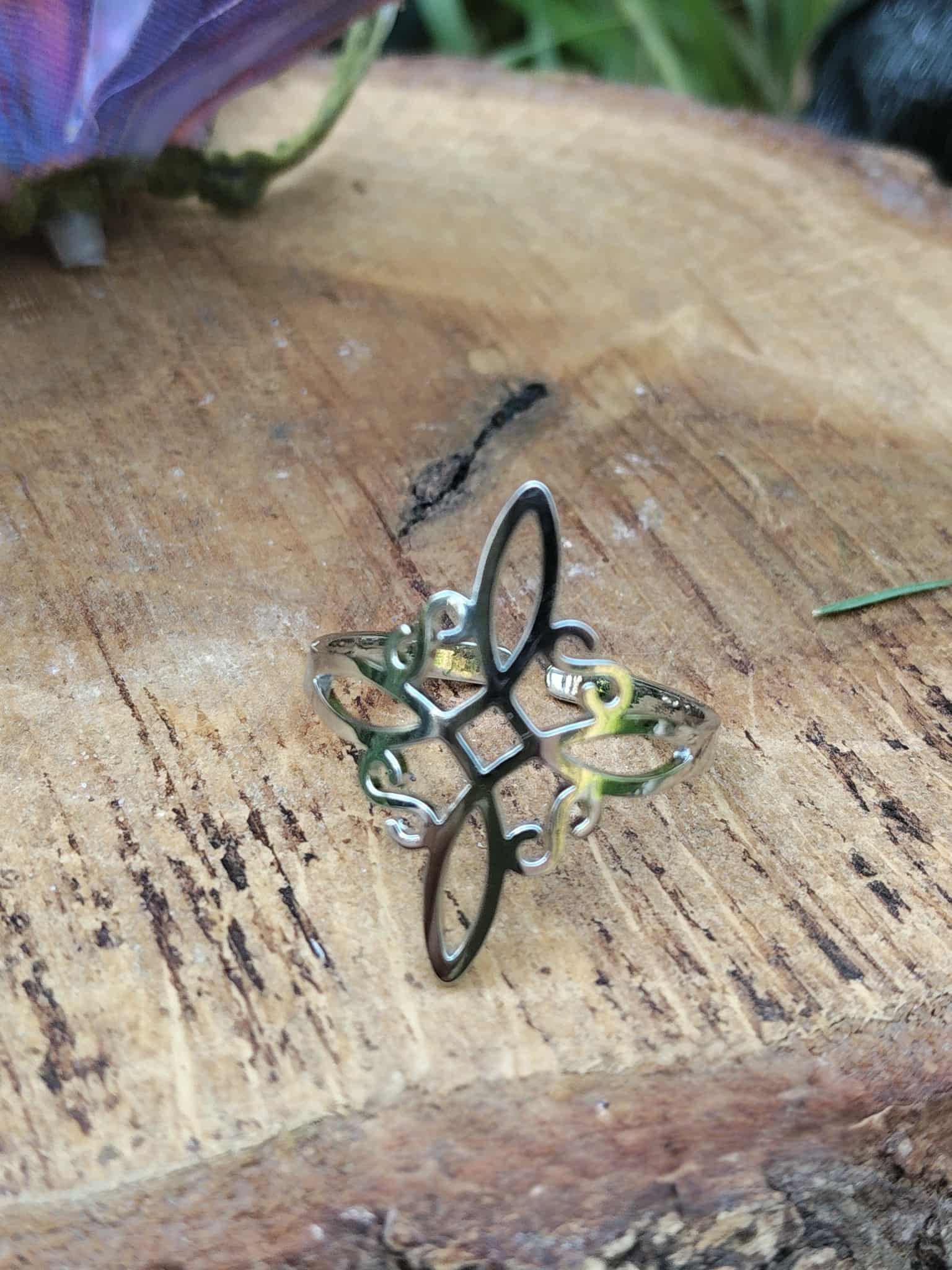 Bague ésotérique nœud de sorcière, talisman de protection, posée sur rondin