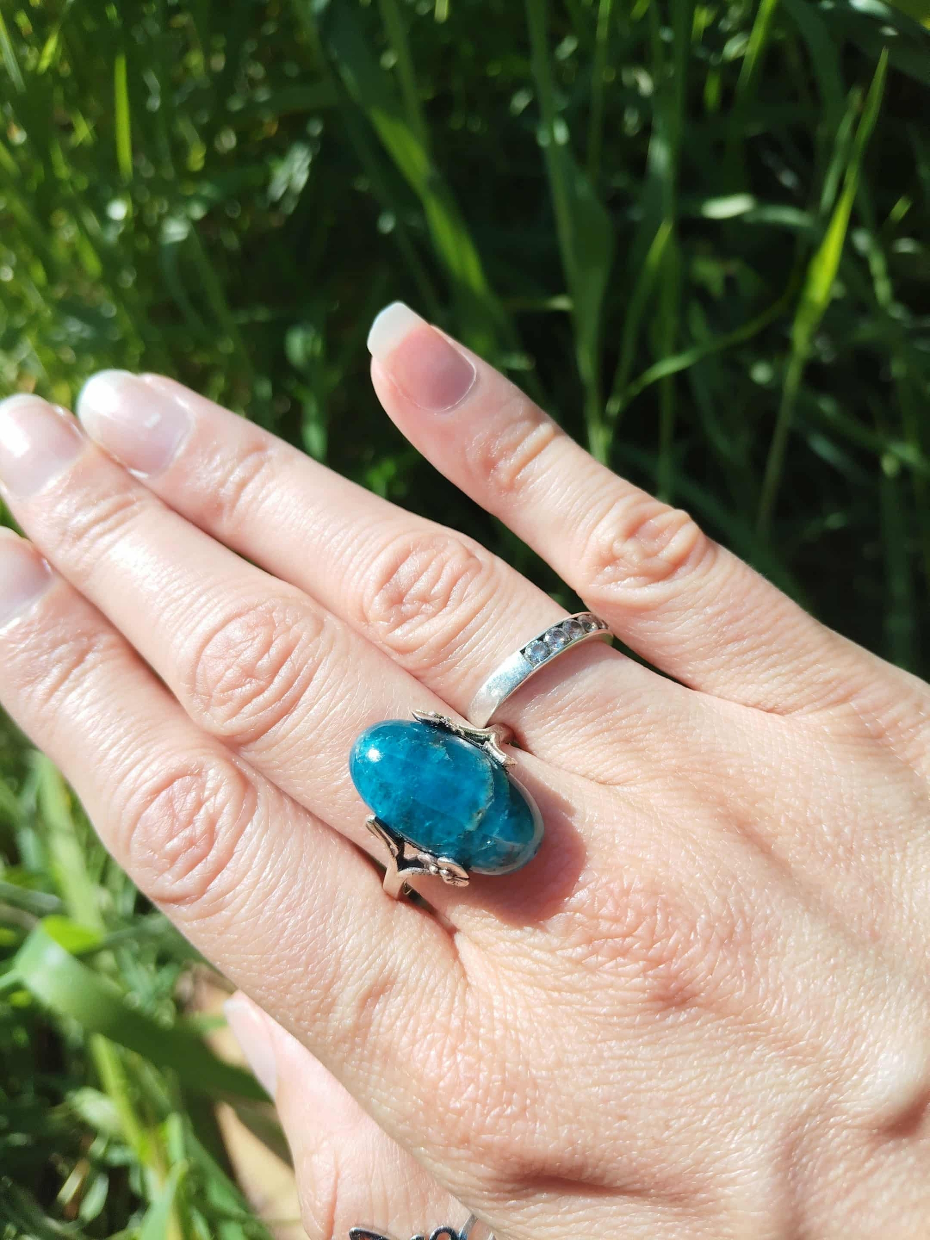 Bague apatite bleue réglable au doigt, fond herbe — confiance en soi, calme du mental, communication bienveillante.