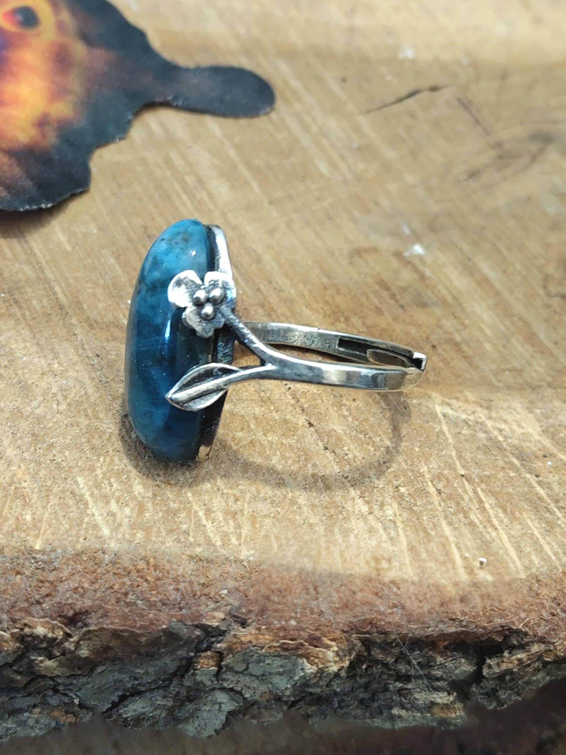 Bague apatite bleue argent 925 réglable, vue de profil sur rondin ; papillon flou — communication, clarté mentale, équilibre émotionnel.