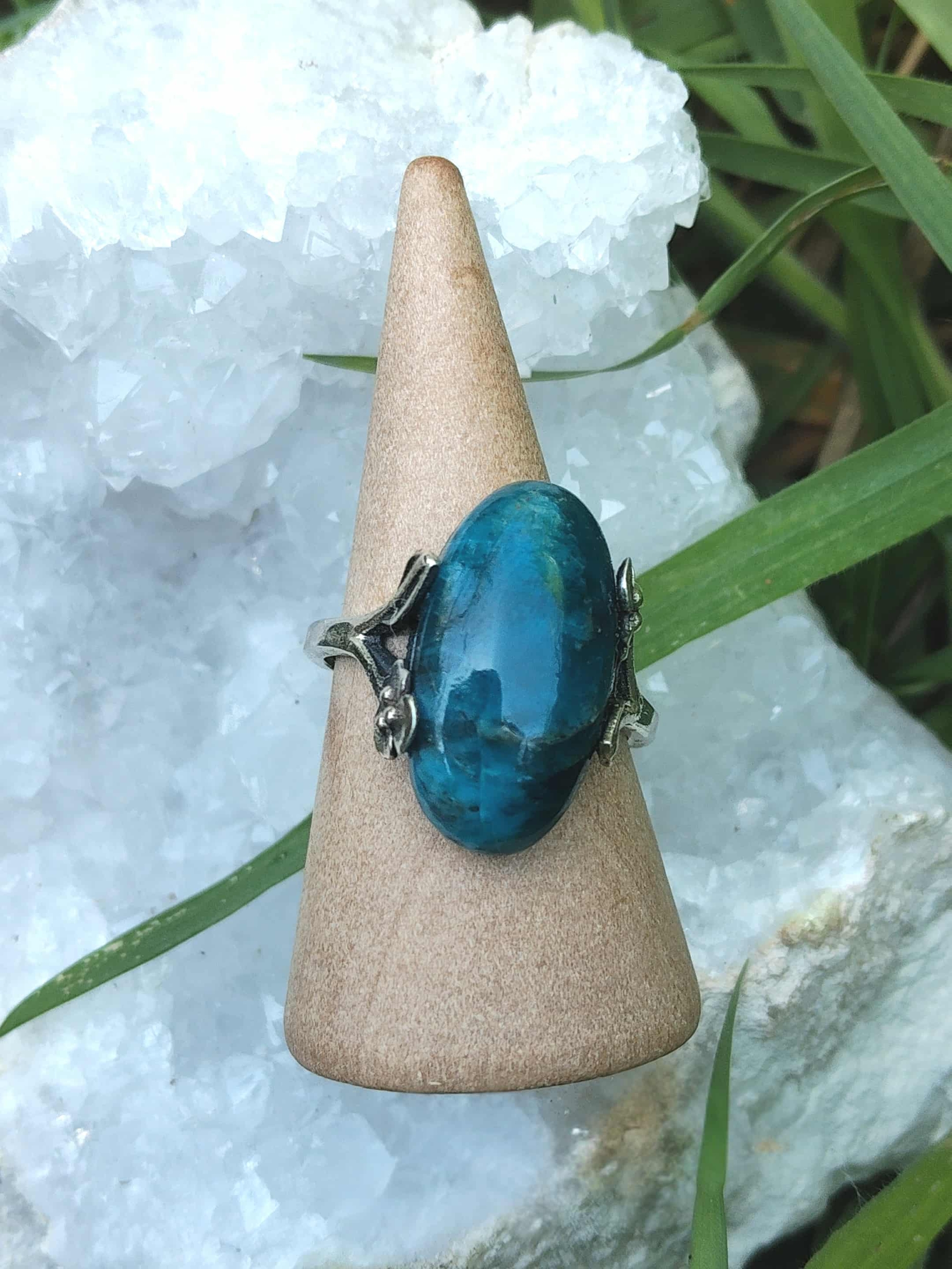 Bague apatite bleue réglable en argent 925 sur cône en bois, devant un amas de quartz — communication, clarté mentale, équilibre émotionnel.
