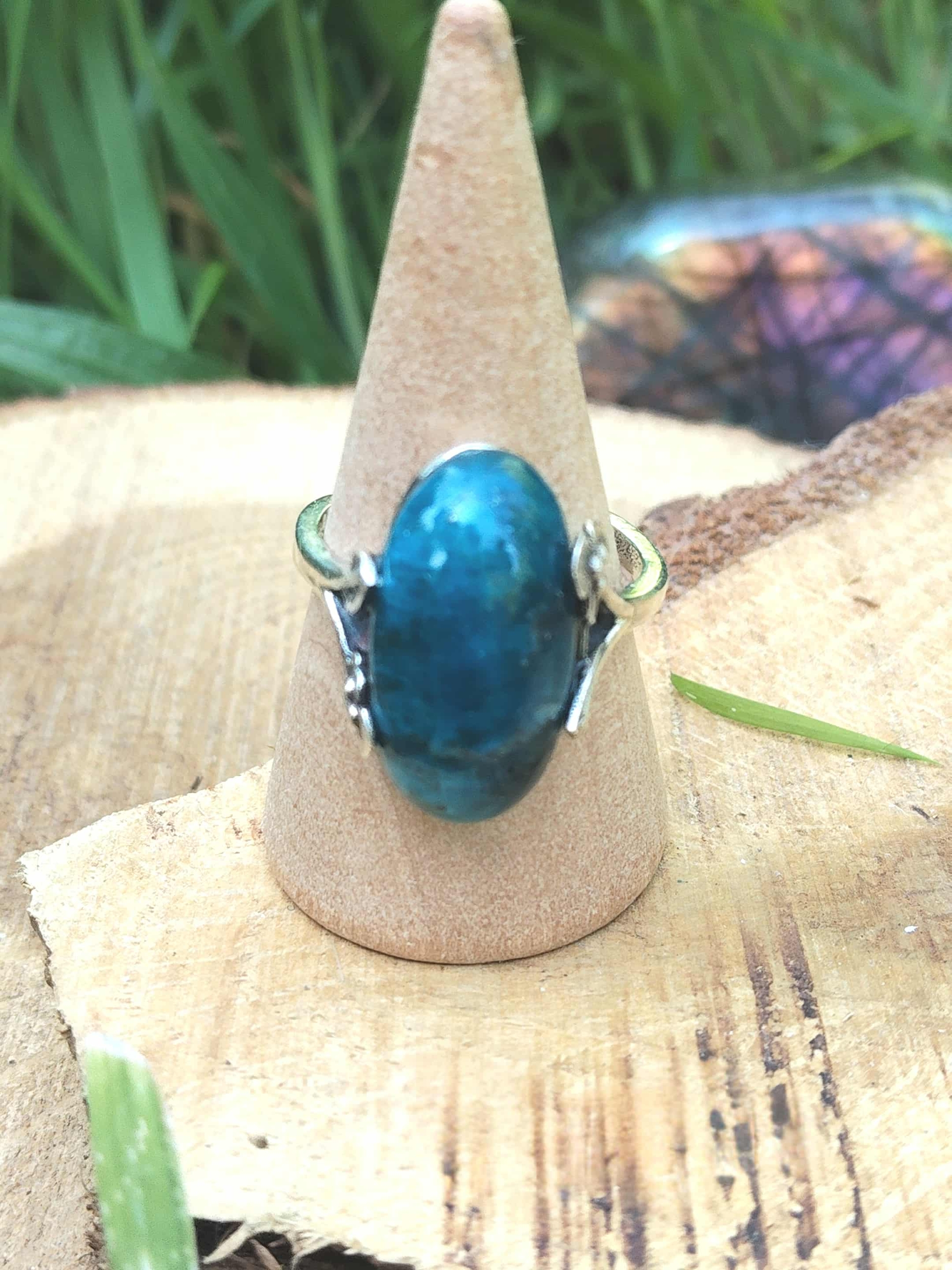 Bague apatite bleue réglable en argent 925 sur cône bois, rondin et herbe, papillon flou — communication, clarté mentale, équilibre émotionnel.