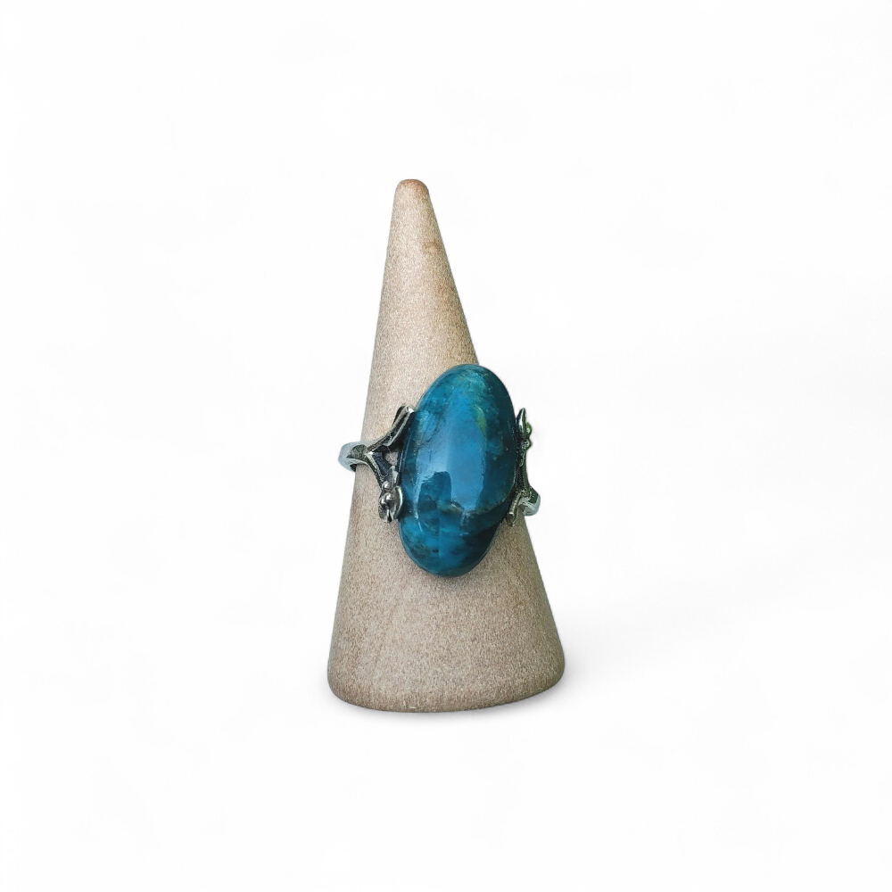 bague-apatite-bleue-reglable-en-argent-925-sur-cone-en-bois-devant-un-amas-de-quartz-communication-clarte-mentale-equilibre-emotionnel