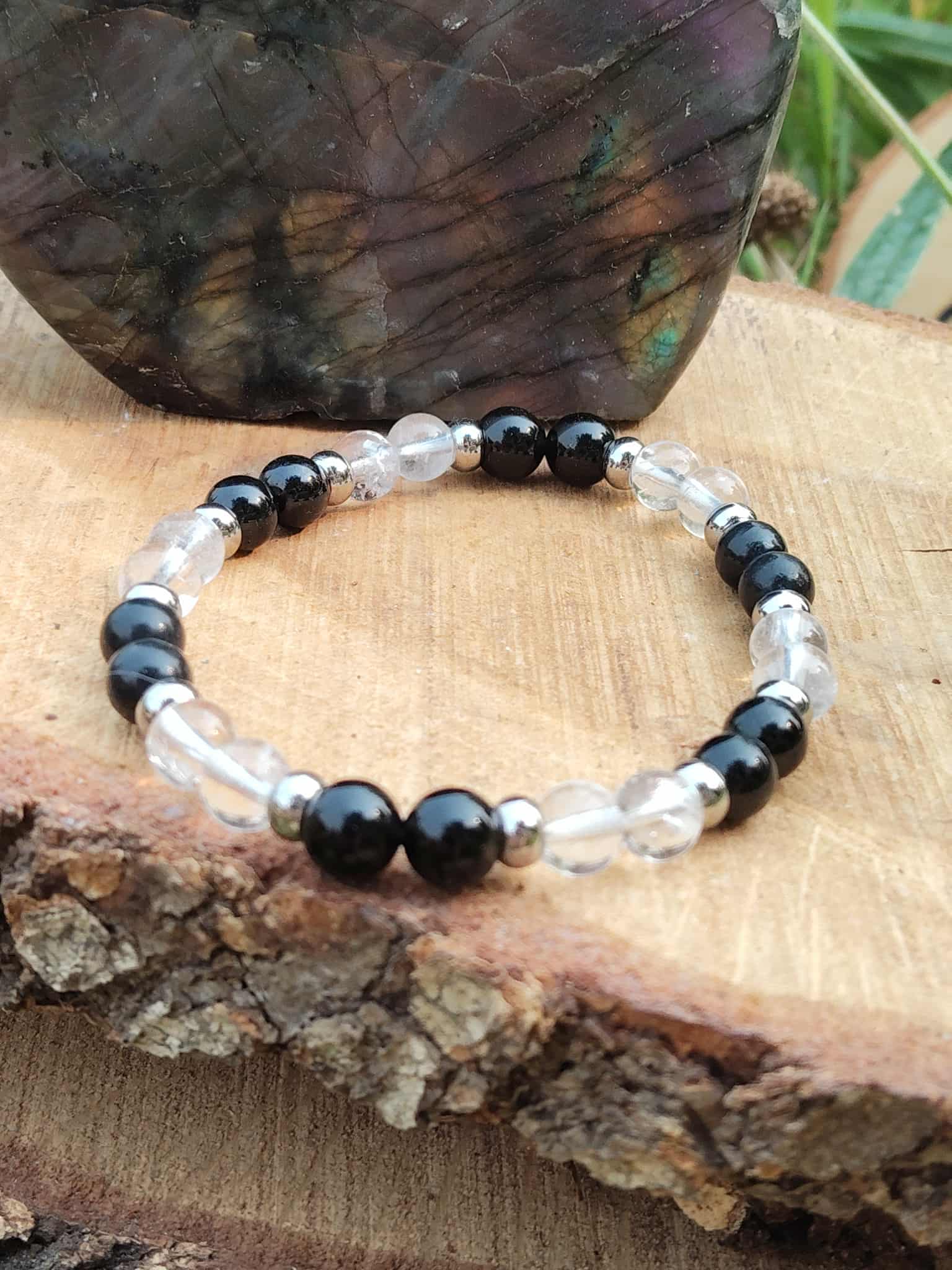 Bracelet protection posé sur bois brut avec fond pierre irisée, trio shungite, tourmaline noire et cristal de roche pour tri émotionnel et solidité intérieure
