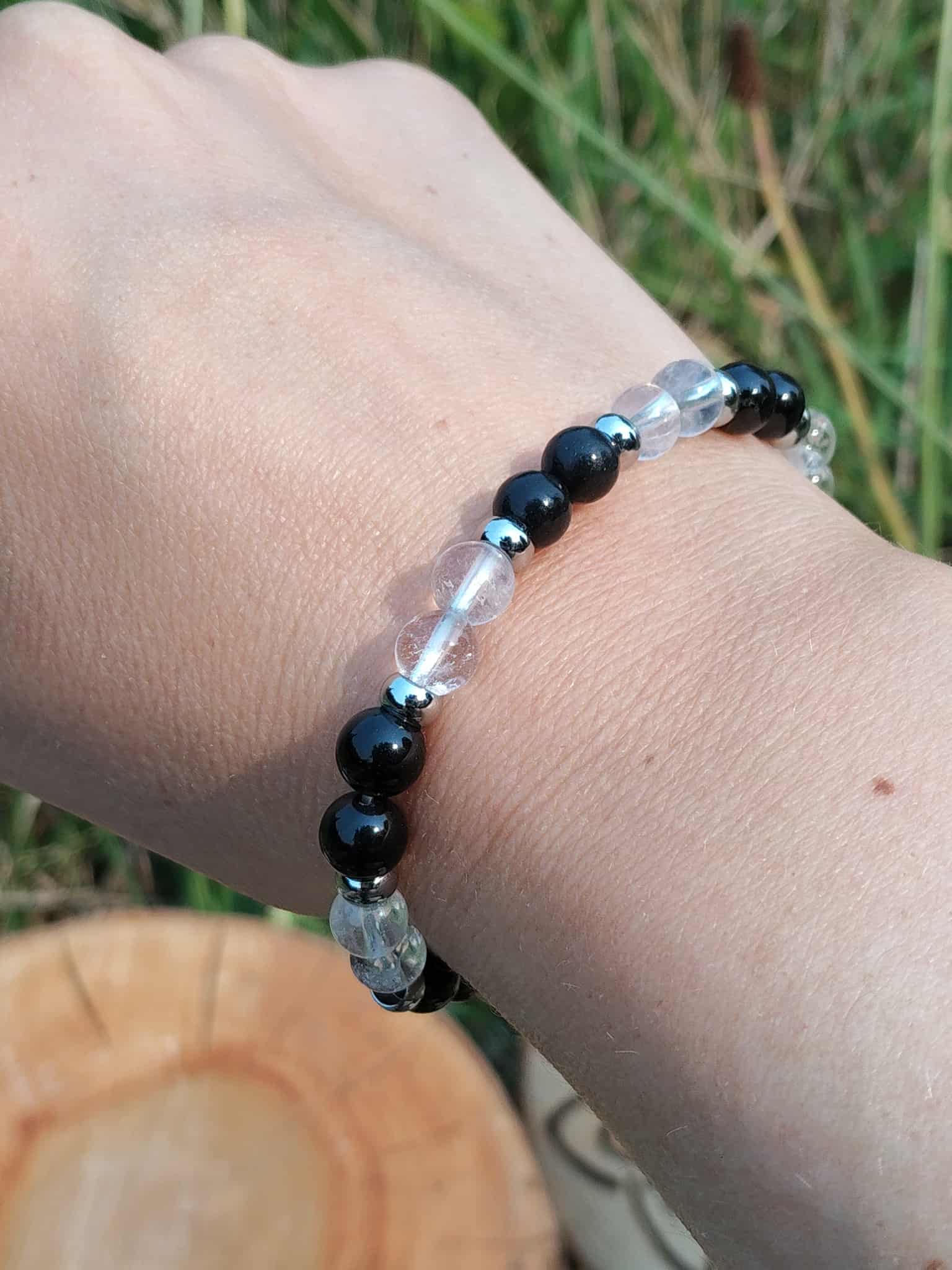 Bracelet énergie négative porté au poignet en extérieur, perles noires et cristal de roche pour se préserver des influences lourdes et garder son axe