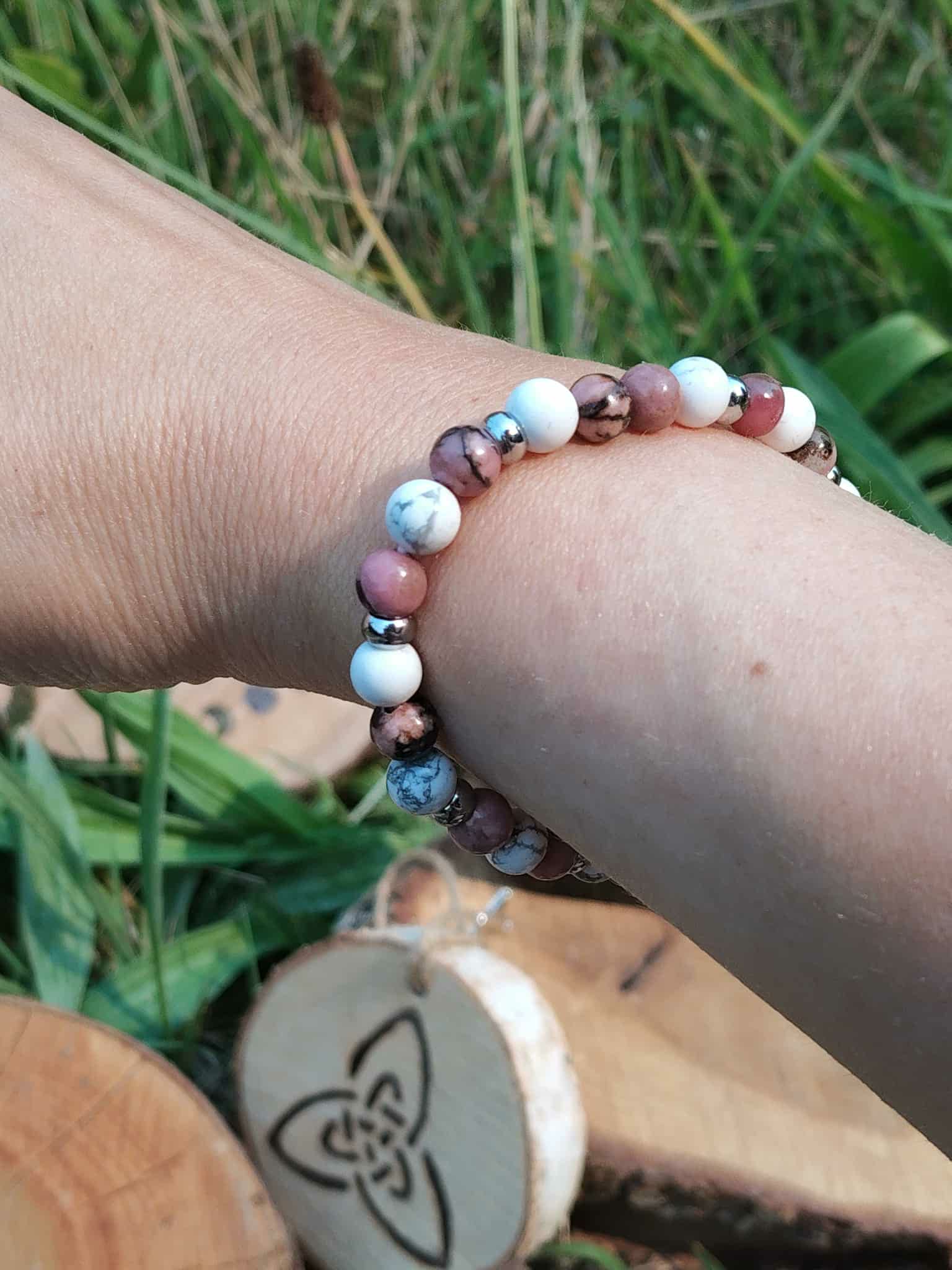 Bracelet déblocages émotionnels howlite et rhodonite porté au poignet, décor nature, apaisement du ressenti et sérénité relationnelle